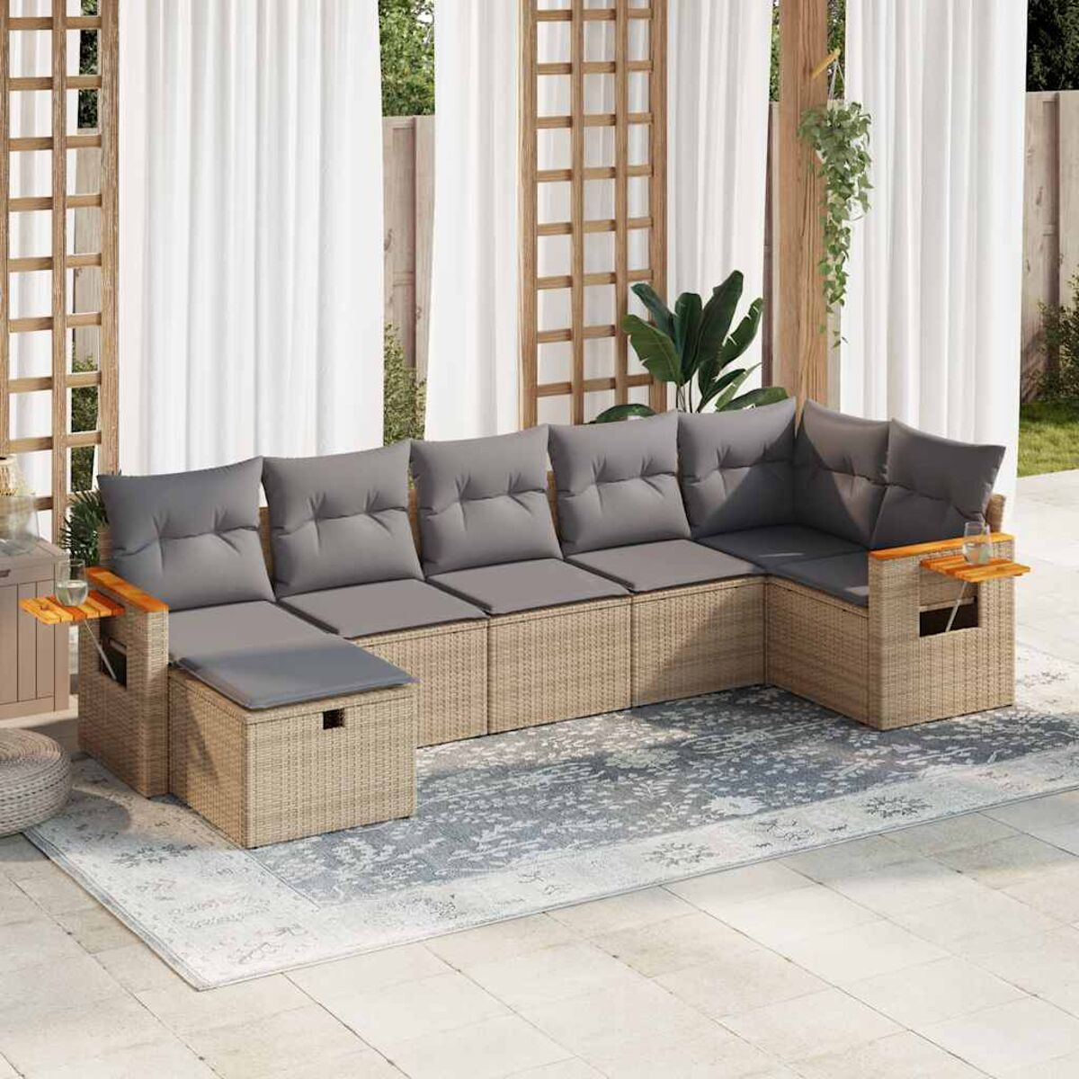 L-förmiges Outdoor-Wicker-Sofa mit grauen Kissen, Holztischen und einem gemusterten Teppich auf einer Terrasse.
