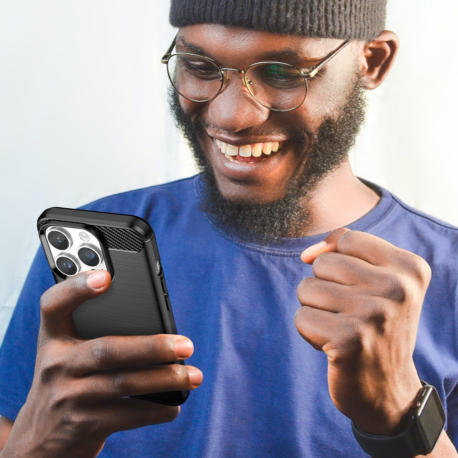 Hombre con gafas sosteniendo un teléfono negro con funda, sonriendo.