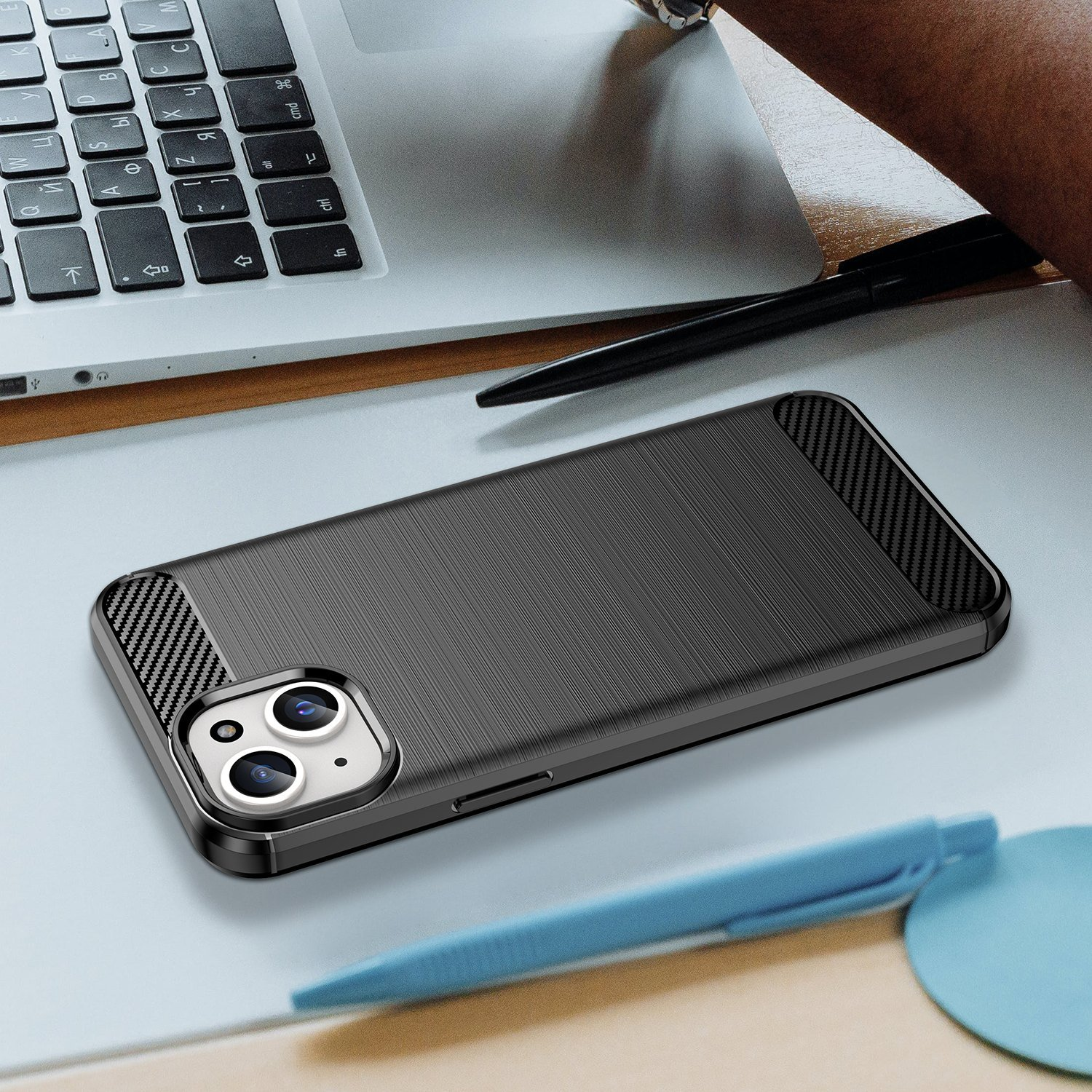 Una funda de teléfono negra sobre una mesa gris junto a un bolígrafo y un portátil.