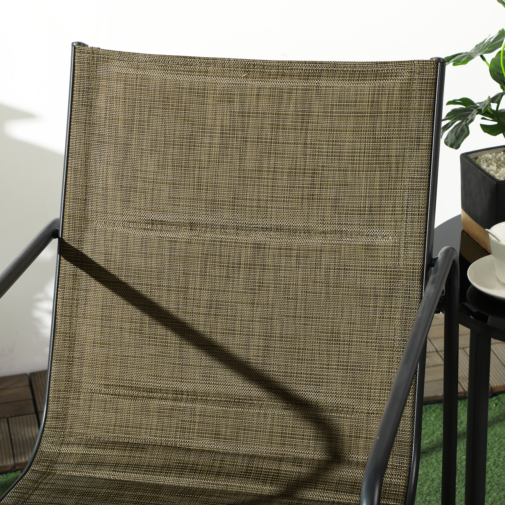 Outdoor-Stuhl mit braun gewebtem Sitz, schwarzem Rahmen und Beistelltisch mit Pflanze.