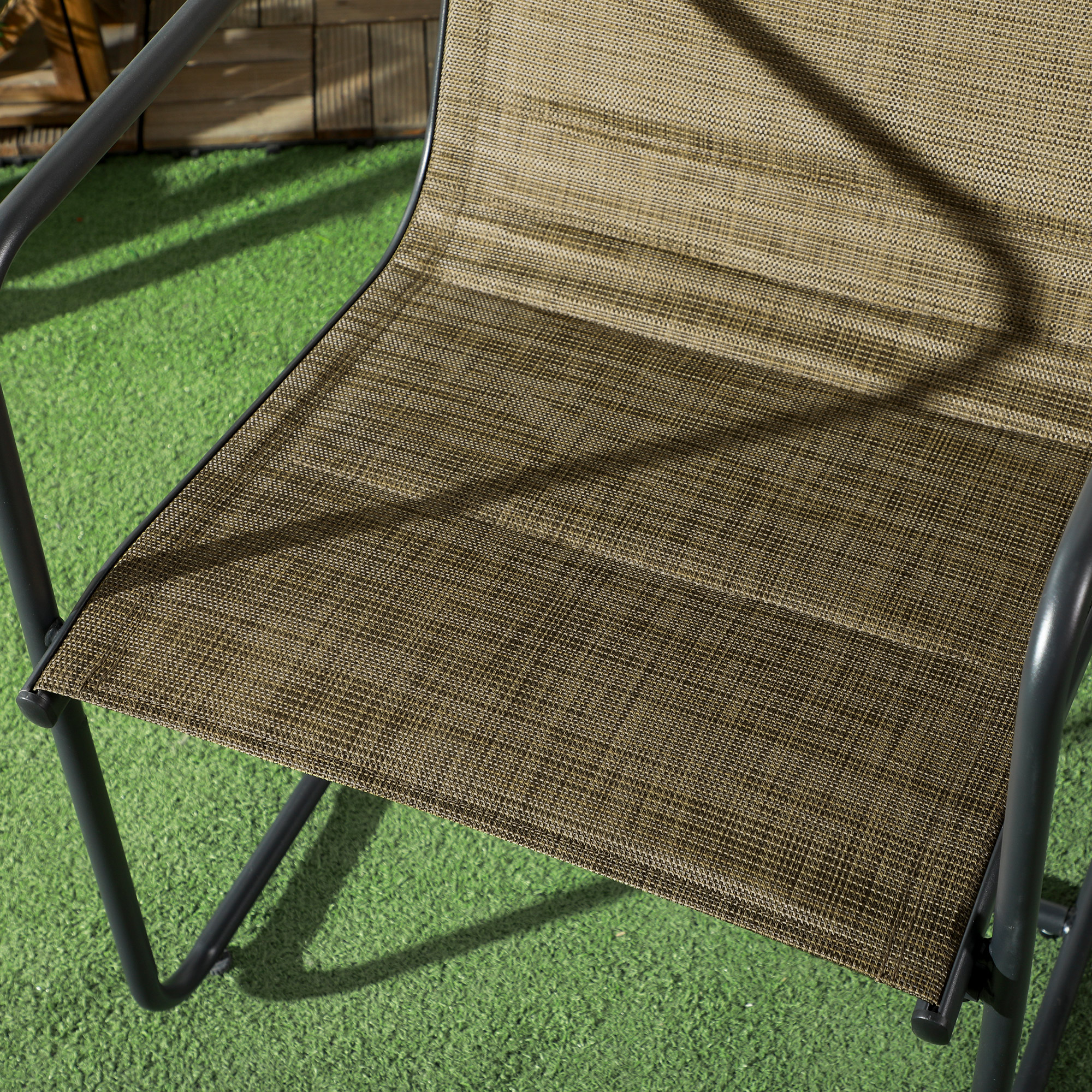Nahaufnahme eines braunen Outdoor-Stuhls auf grünem Gras. Der Stuhl hat einen gewebten Sitz und Metallrahmen.