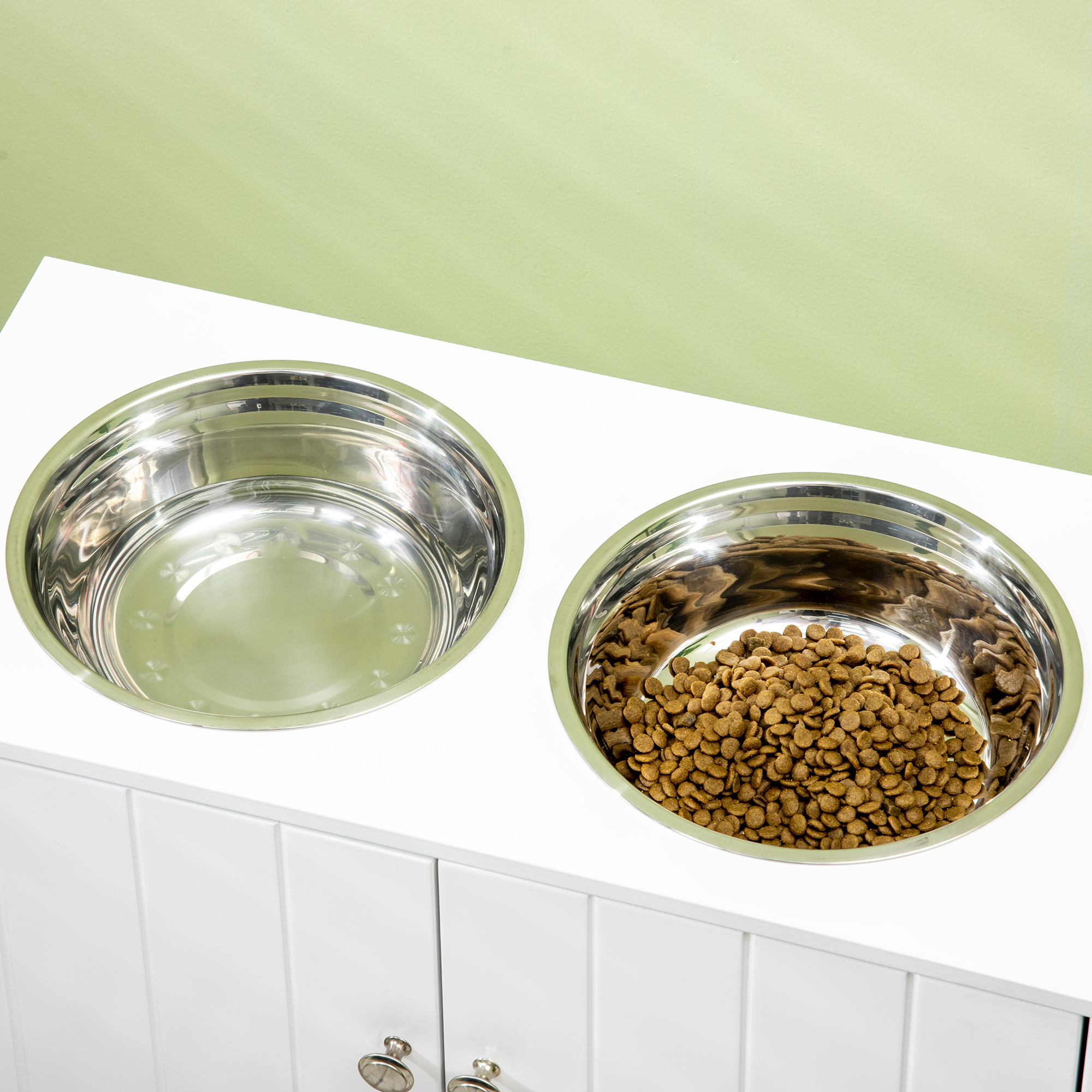 Dos cuencos de acero inoxidable para perros en una encimera blanca, uno con comida.
