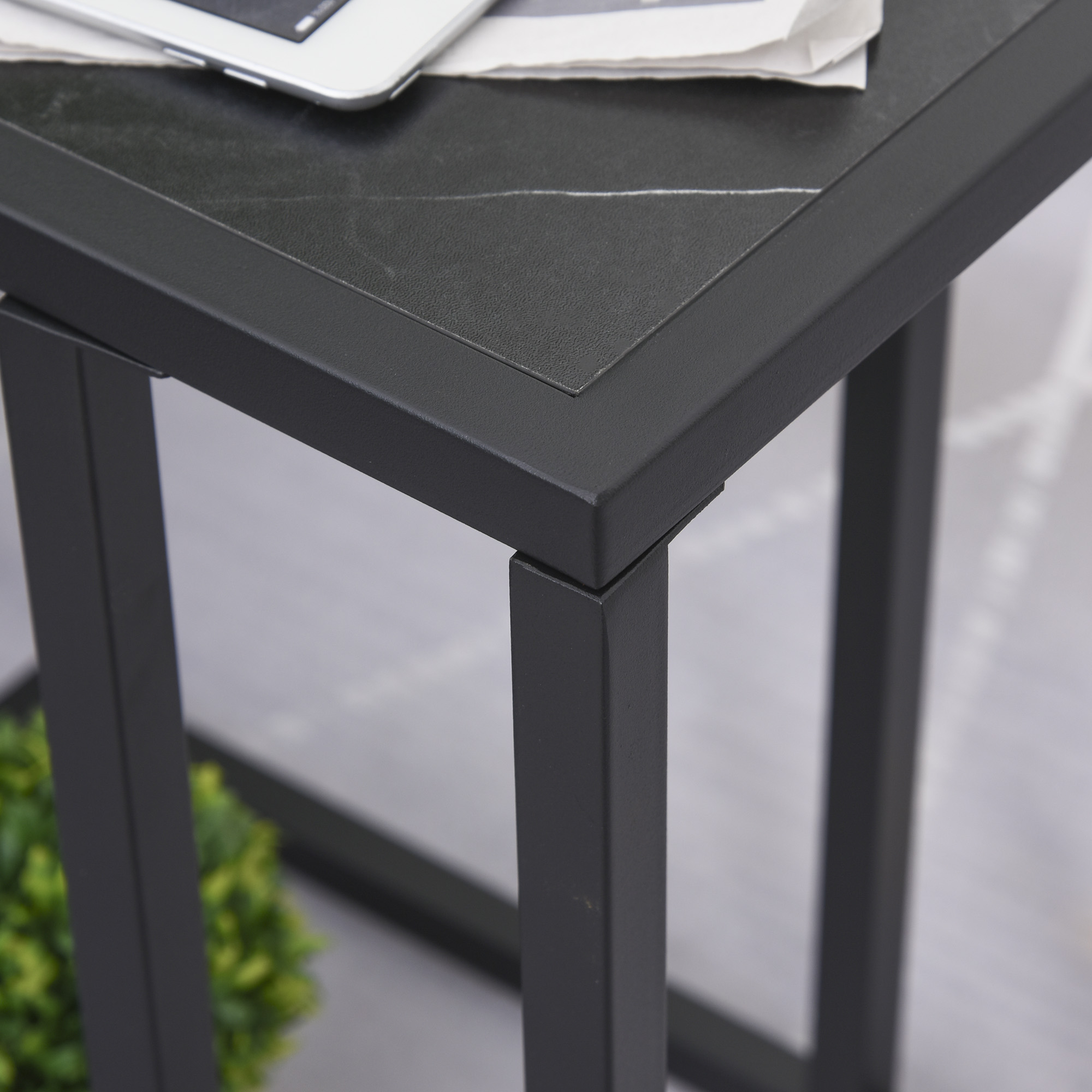 Schwarzer Tisch mit Marmorplatte. Metallrahmen. Tablet und Zeitung, Pflanze.