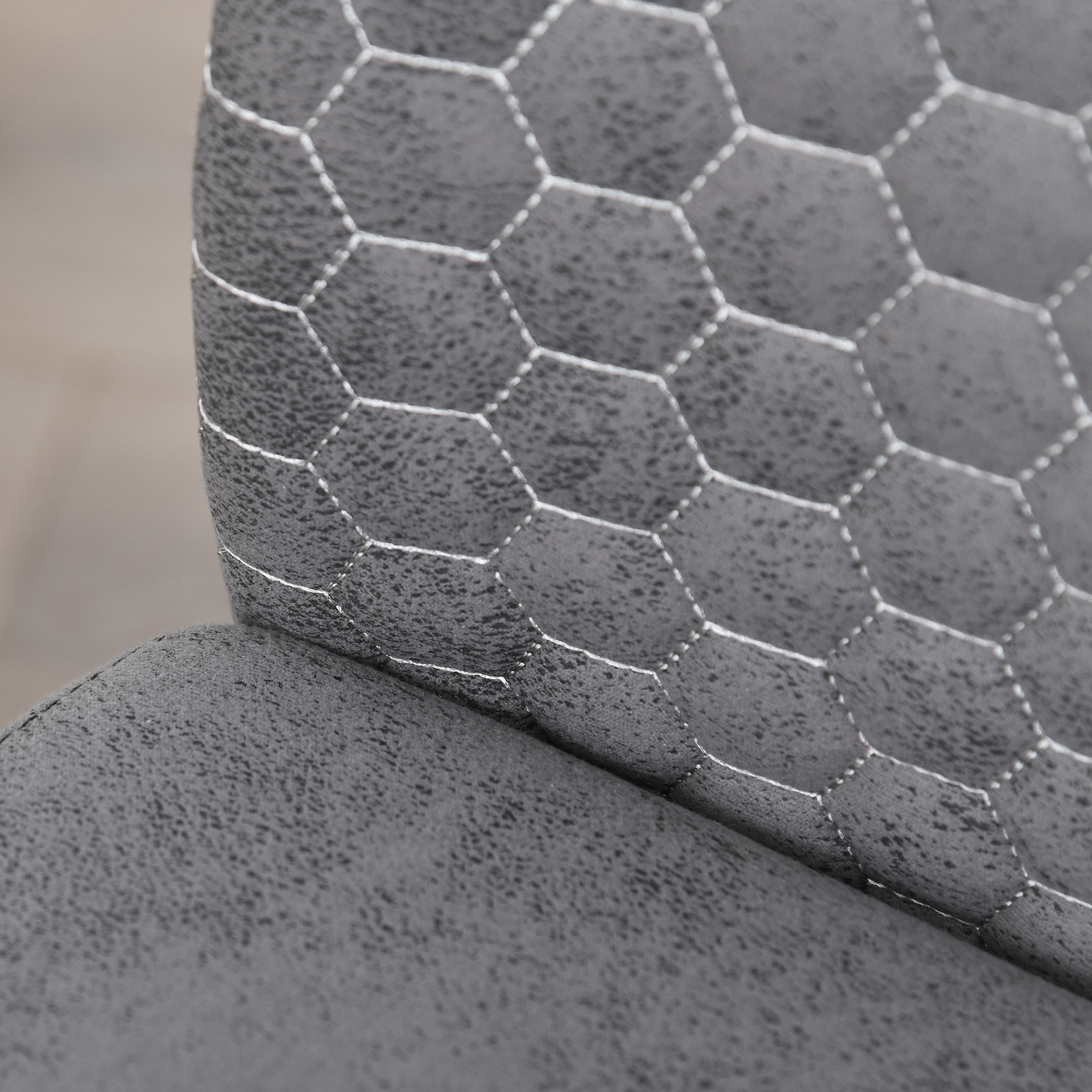 Primer plano de tapicería de silla gris con patrón hexagonal y costuras blancas.