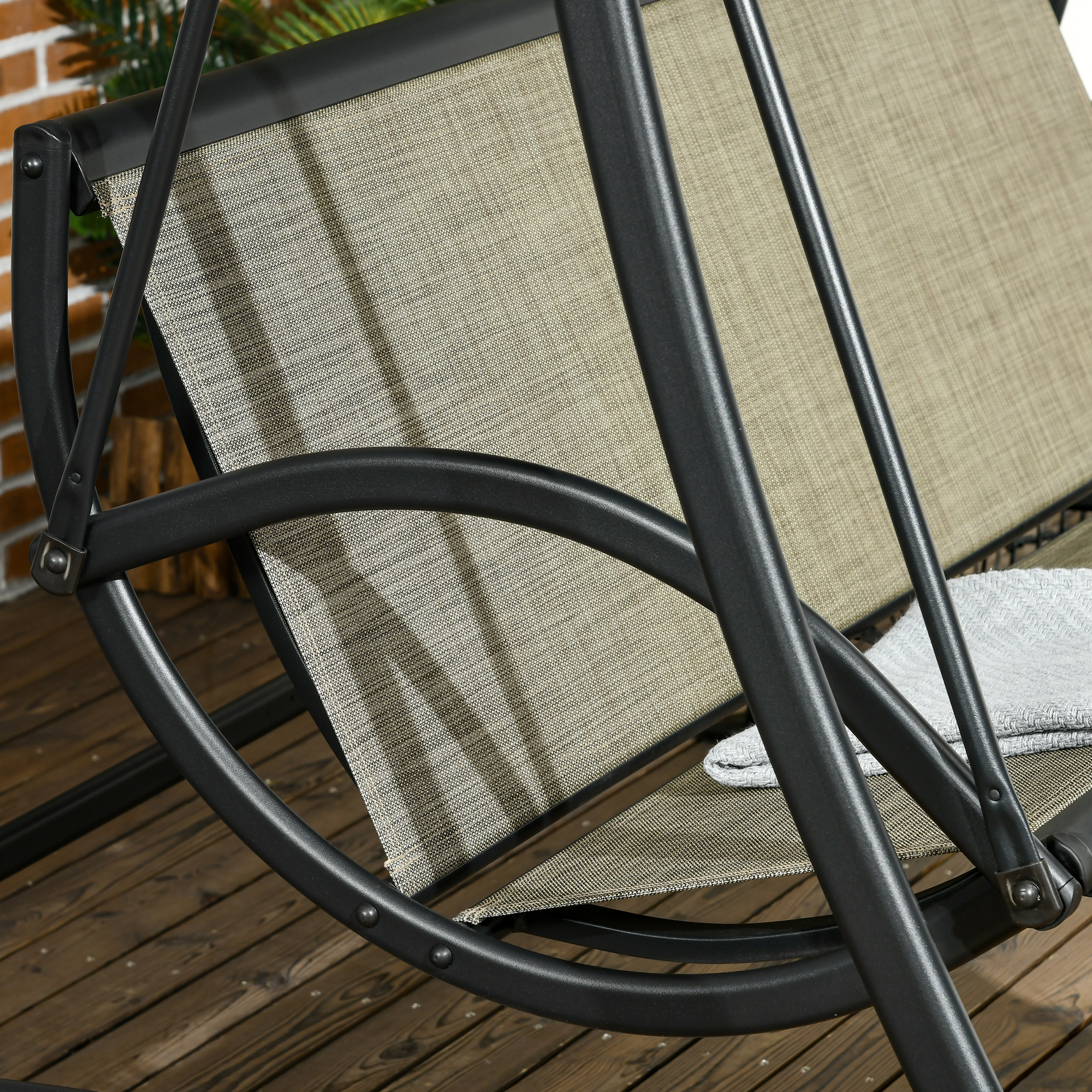 Ein schwarzes Outdoor-Schaukelset mit beigefarbenen Stoffsitzen. Die Schaukel steht auf einem Holzdeck.