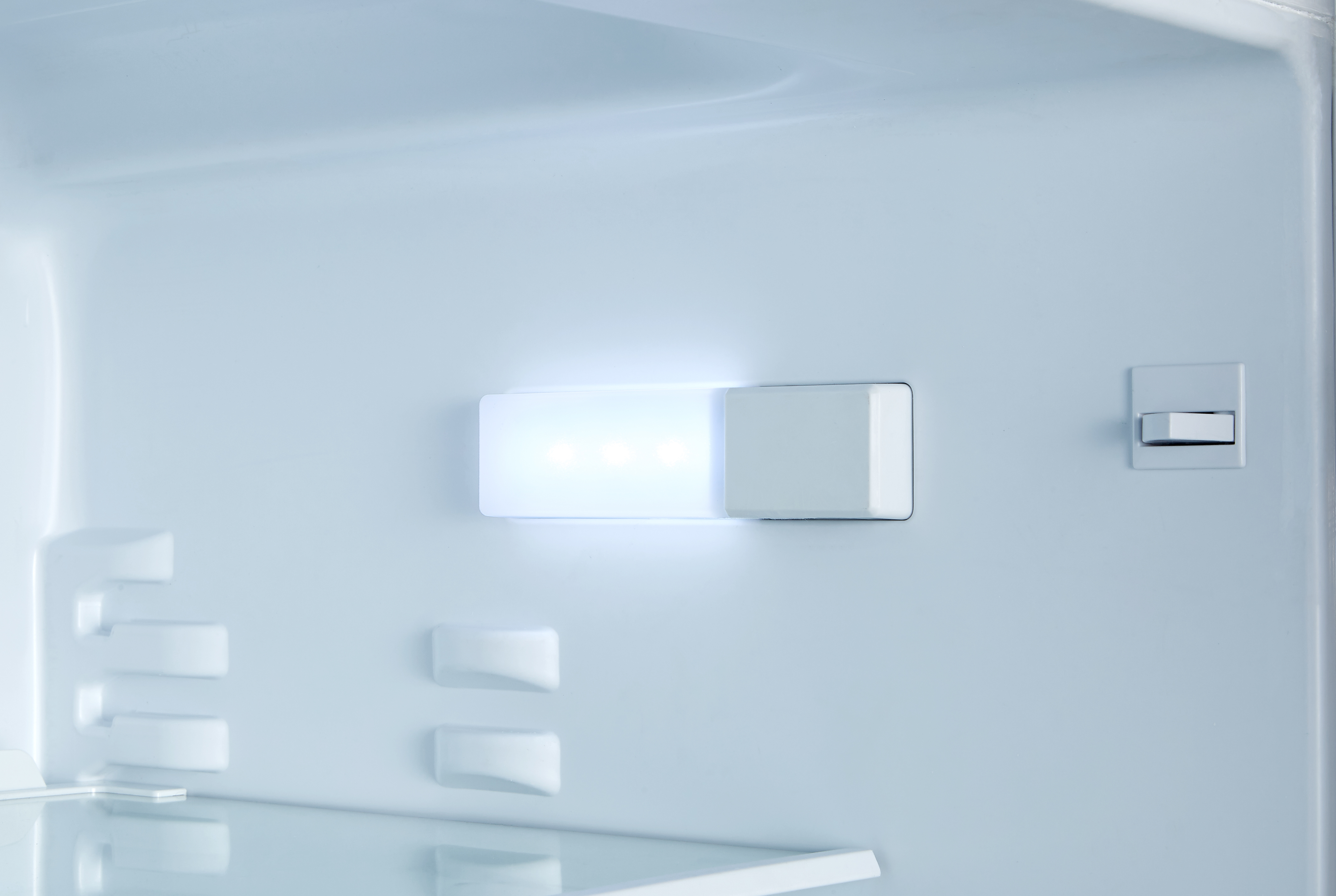 Innenraum eines Kühlschranks mit hellem LED-Licht und weißen Innenraumkomponenten, sauber und leer.