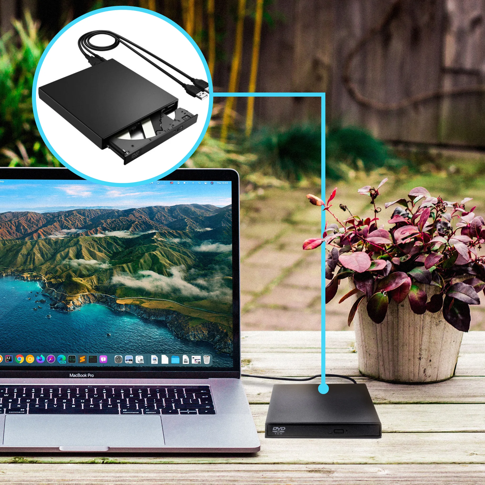 Ein Laptop mit einem schwarzen DVD-Laufwerk, das daran angeschlossen ist. Im Hintergrund sind Strand und Topfpflanze zu sehen.