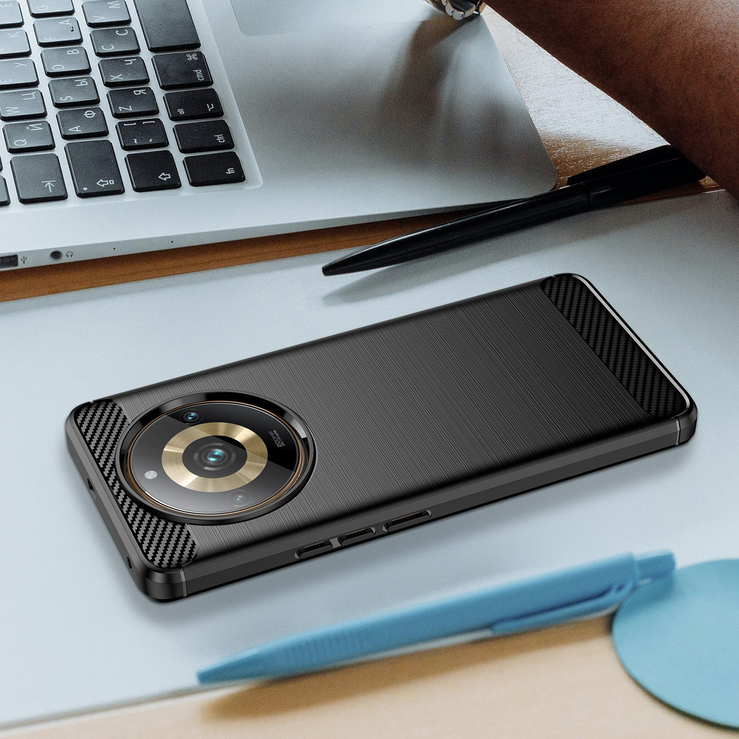 Funda de teléfono negra en un escritorio junto a una laptop y un bolígrafo. Fondo blanco.