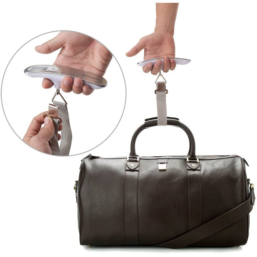 Gepäckwaage mit Koffer. Hand hält Waage mit Gurt am Koffer.