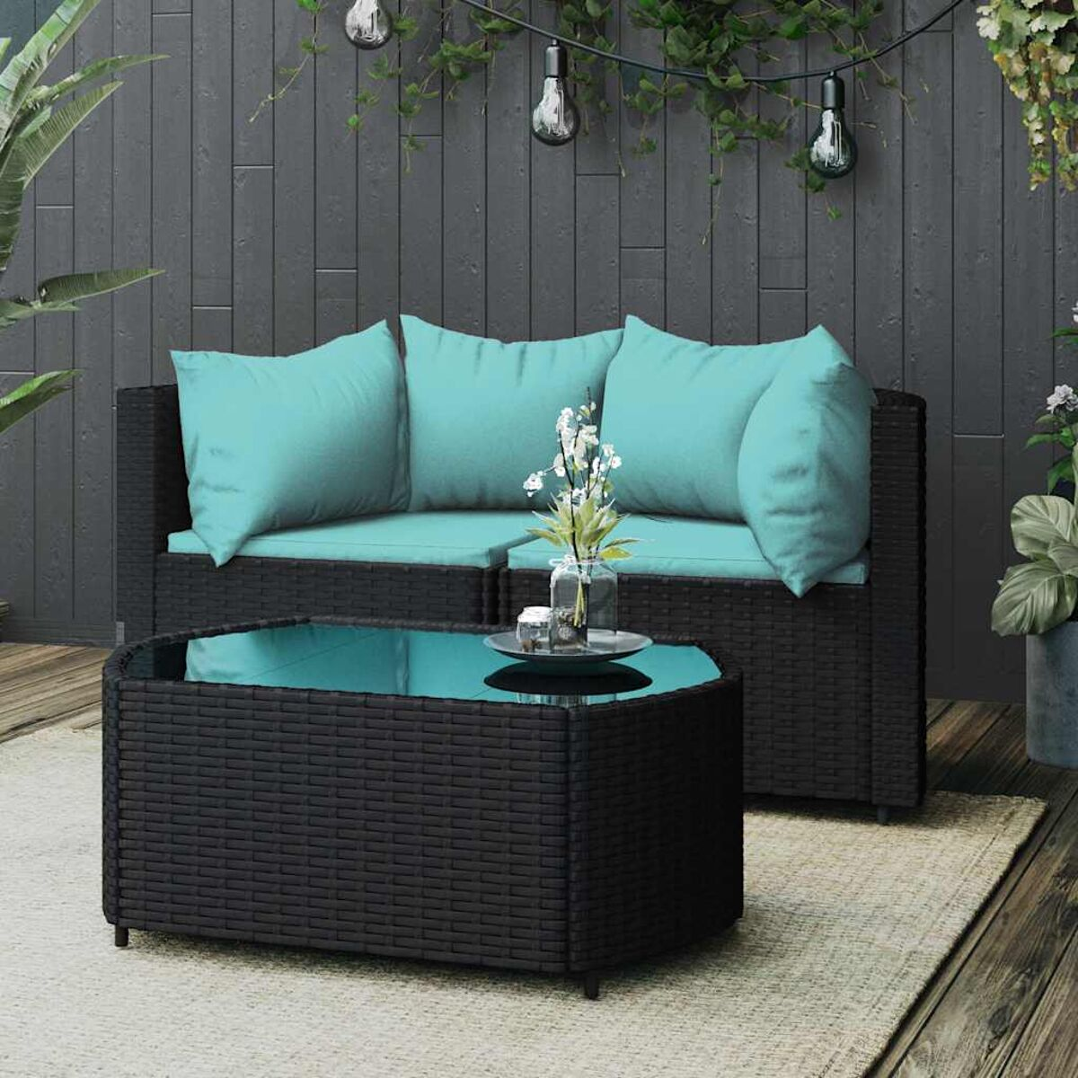 Outdoor-Rattansofa mit türkisfarbenen Kissen und einem Tisch. Der Hintergrund ist eine Terrasse.