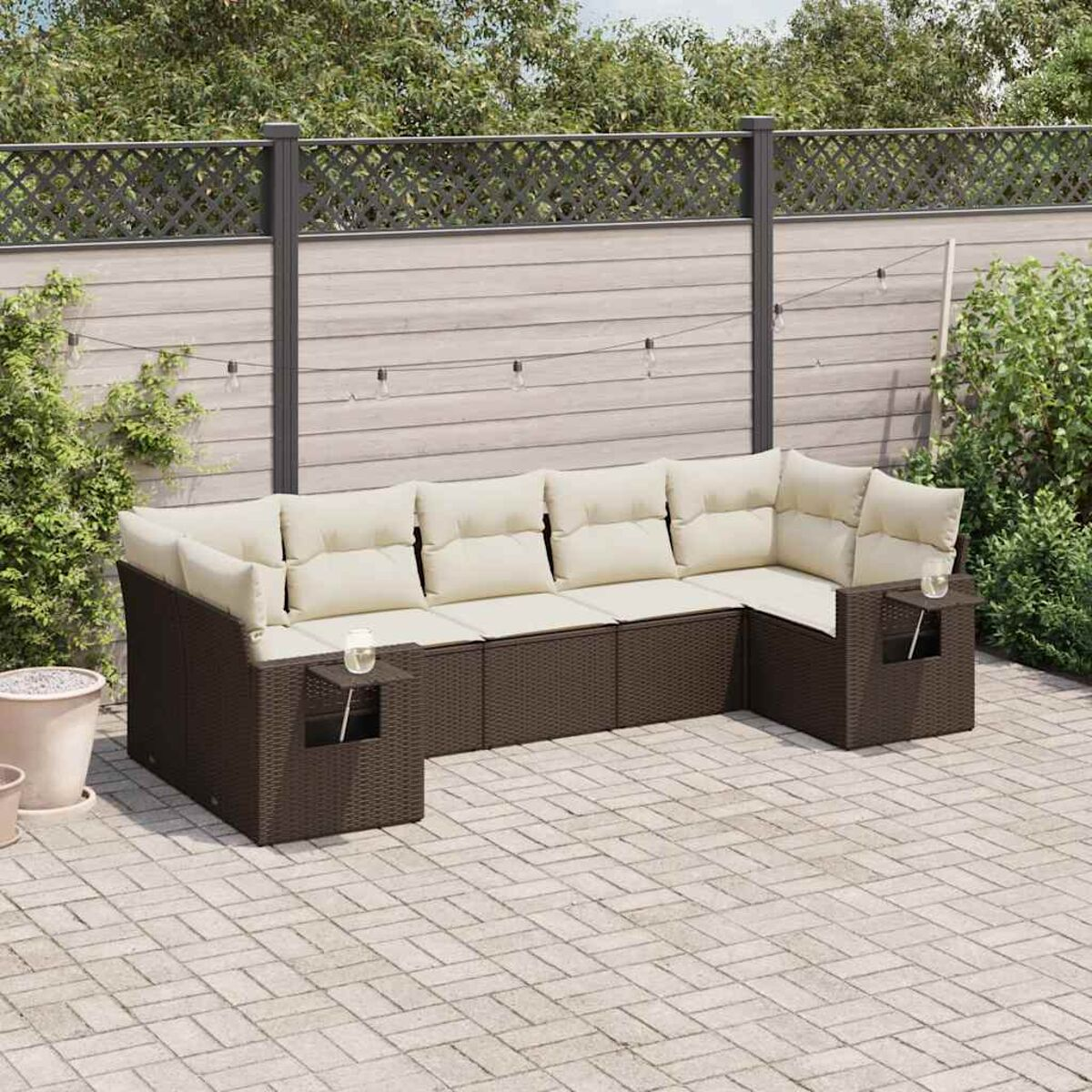 Ein braunes Outdoor-Sofaset aus Korbgeflecht auf einer Steinterrasse.