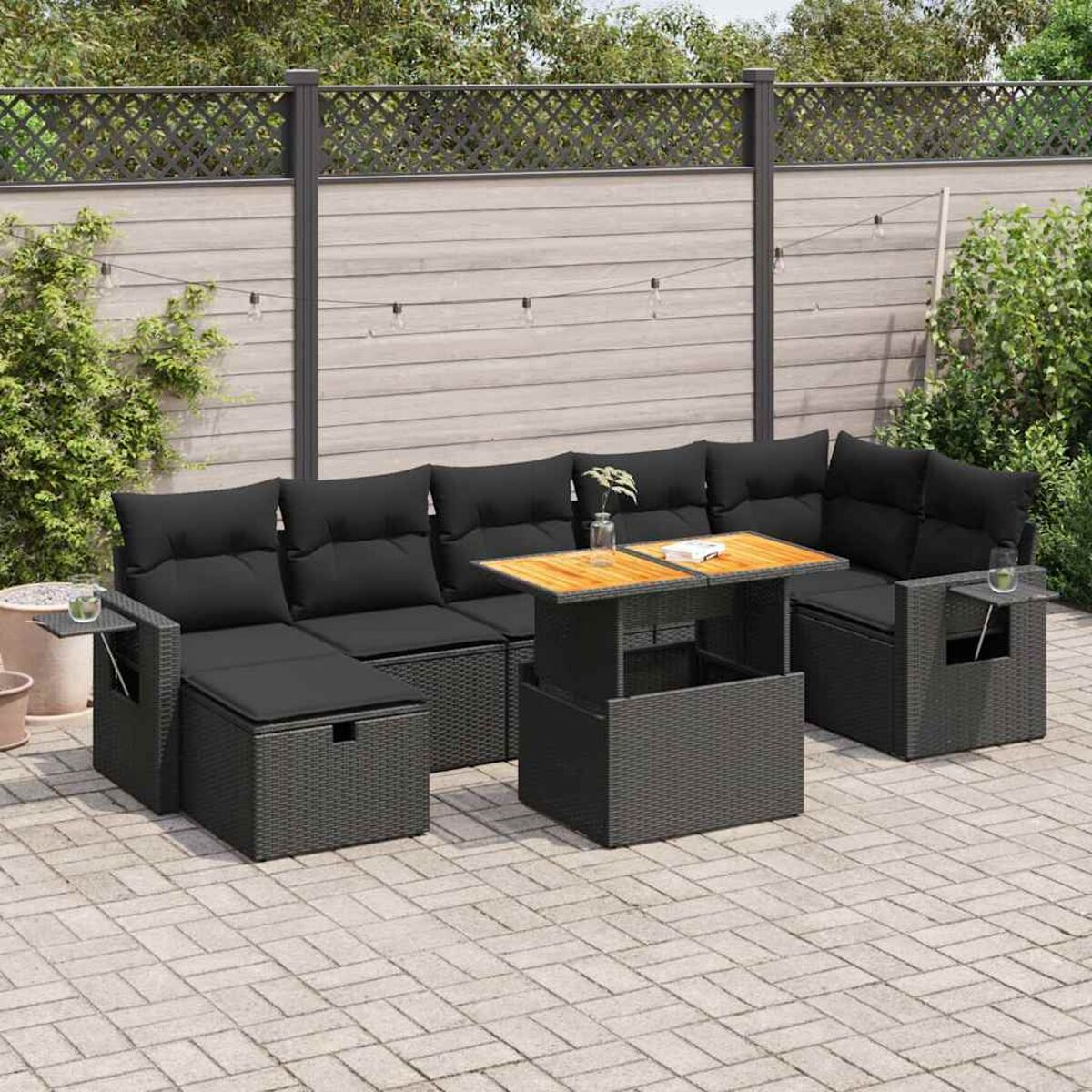 Sitzgruppe im Freien mit schwarzen Kissen, einem Holztisch und einer Backstein-Terrasse.
