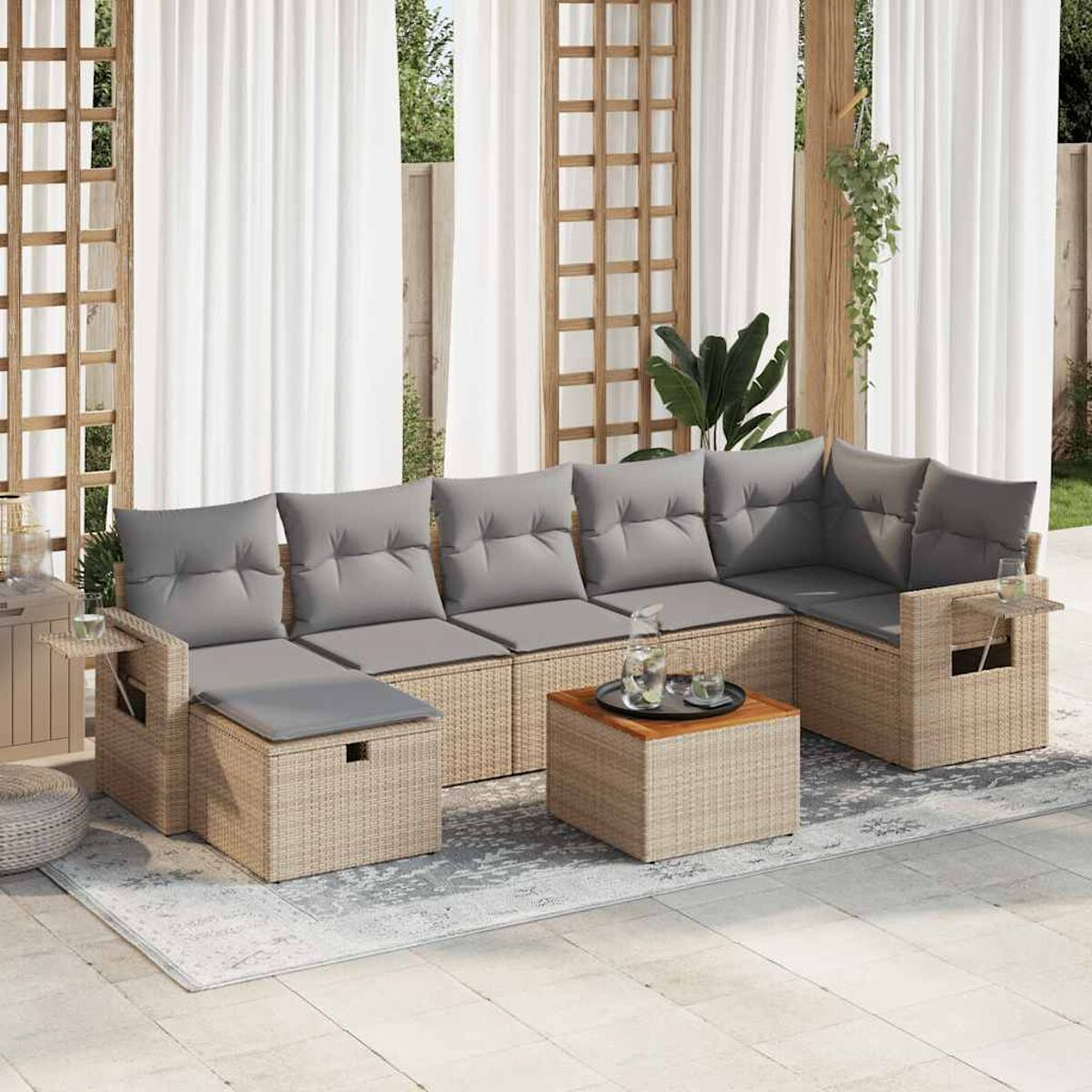 Geflochtenes Outdoor-Ecksofa mit grauen Kissen und einem Holztisch. Vorhänge im Hintergrund.