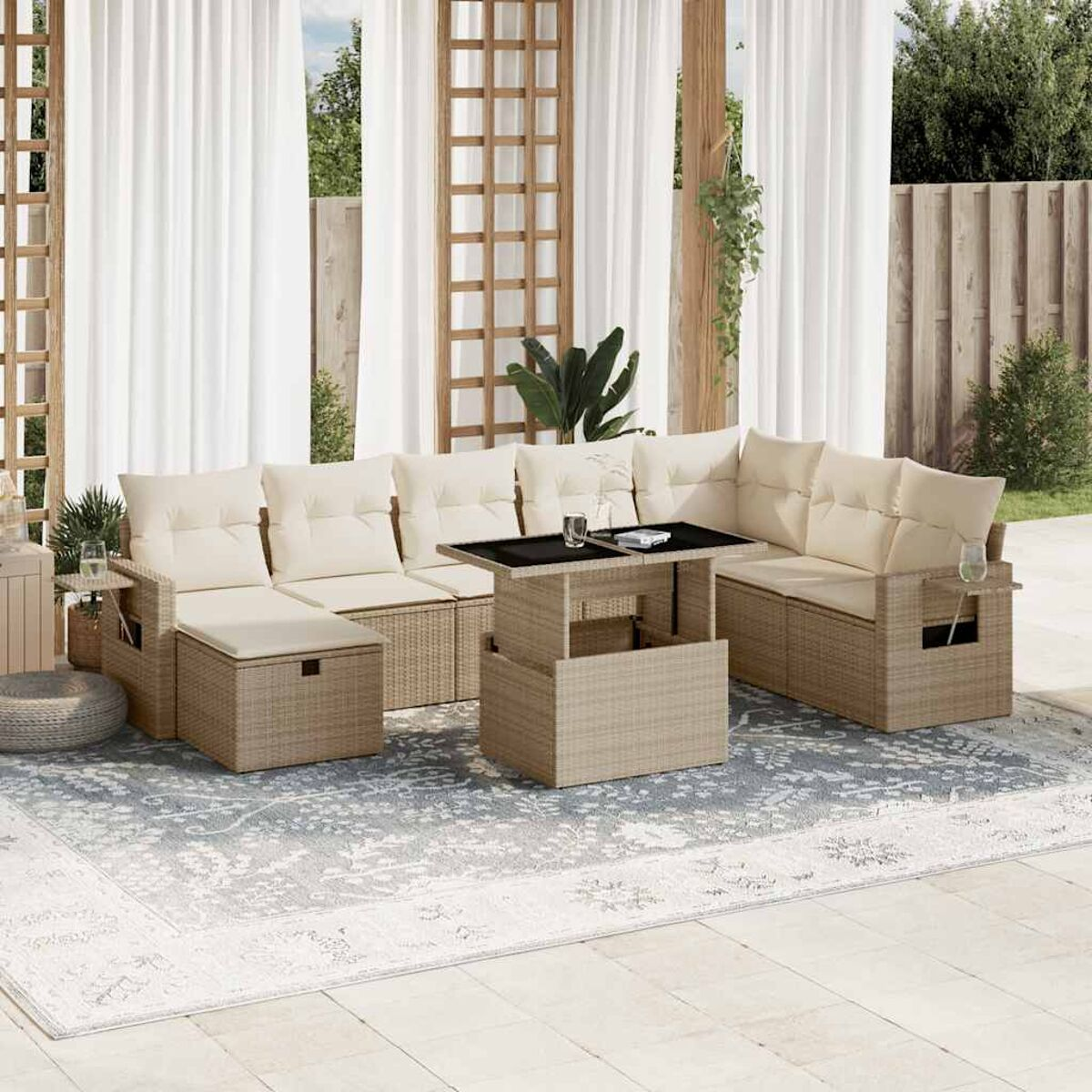 Set divano componibile da esterno. Vimini beige. Cuscini beige. Tavolino. Tende bianche sullo sfondo. Giorno di sole.