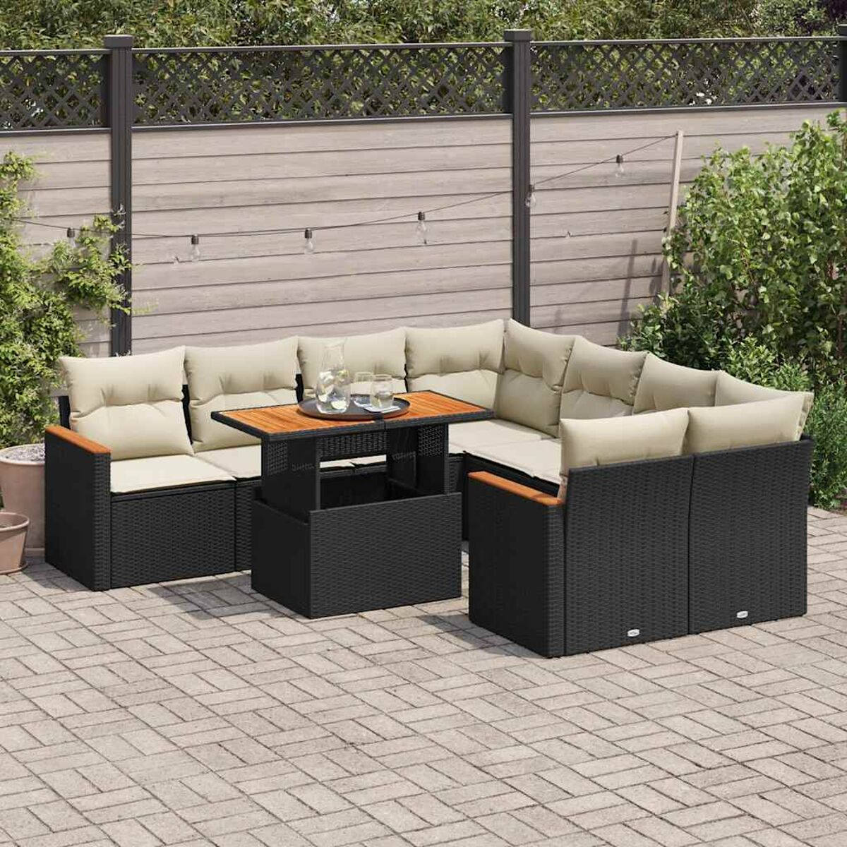 Set di mobili da esterno in vimini nero. Cuscini beige, dettagli in legno e tavolo.