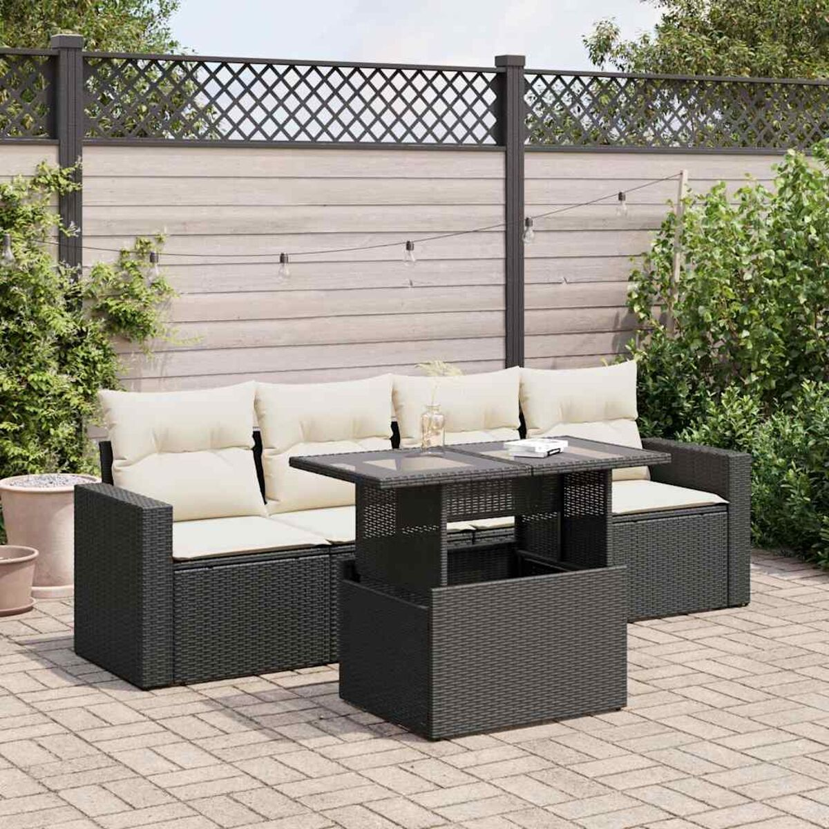 Set da patio esterno con divano, tavolo e recinzione di sfondo.