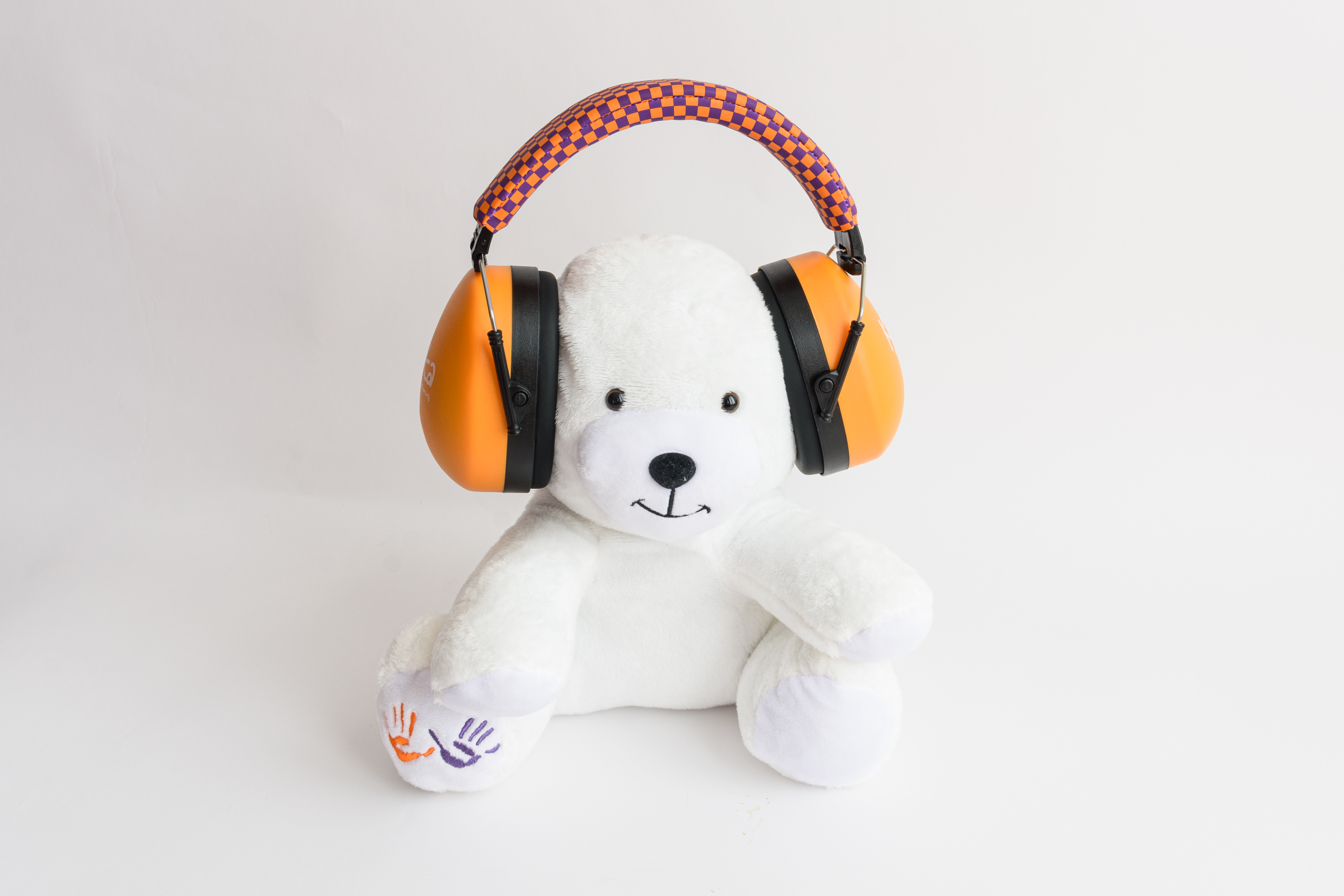 Een witte teddybeer met oranje oorkappen, op een witte achtergrond.
