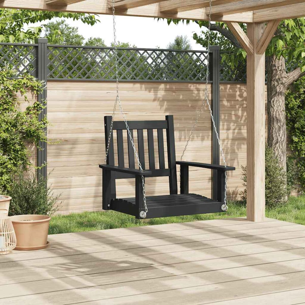 Eine schwarze Holzschaukel, die an einer Holzpergola hängt, mit grünem Hintergrund.