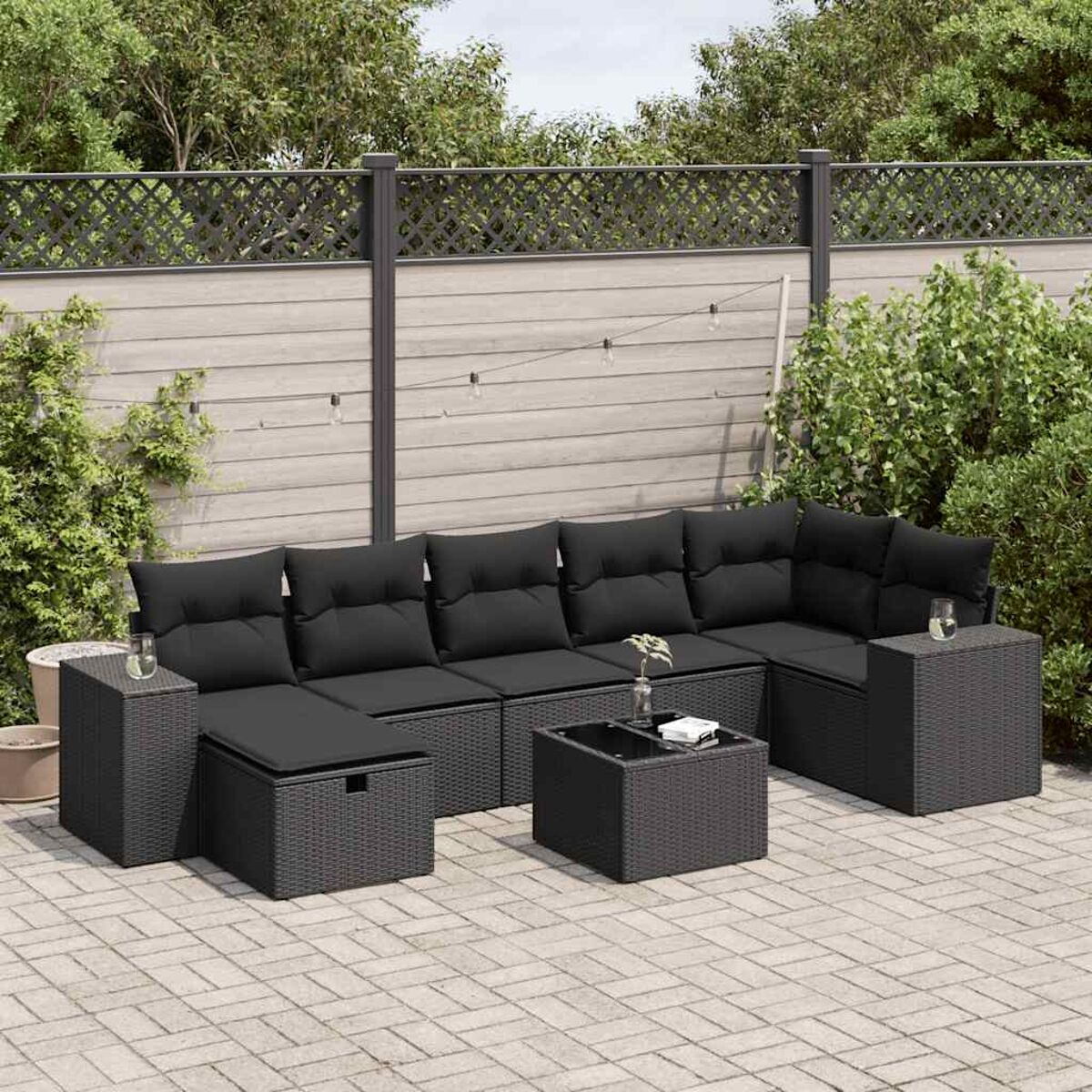Terrassenmöbel-Set. Schwarzes Rattan-Ecksofa mit schwarzen Kissen, Couchtisch und Beistelltischen.