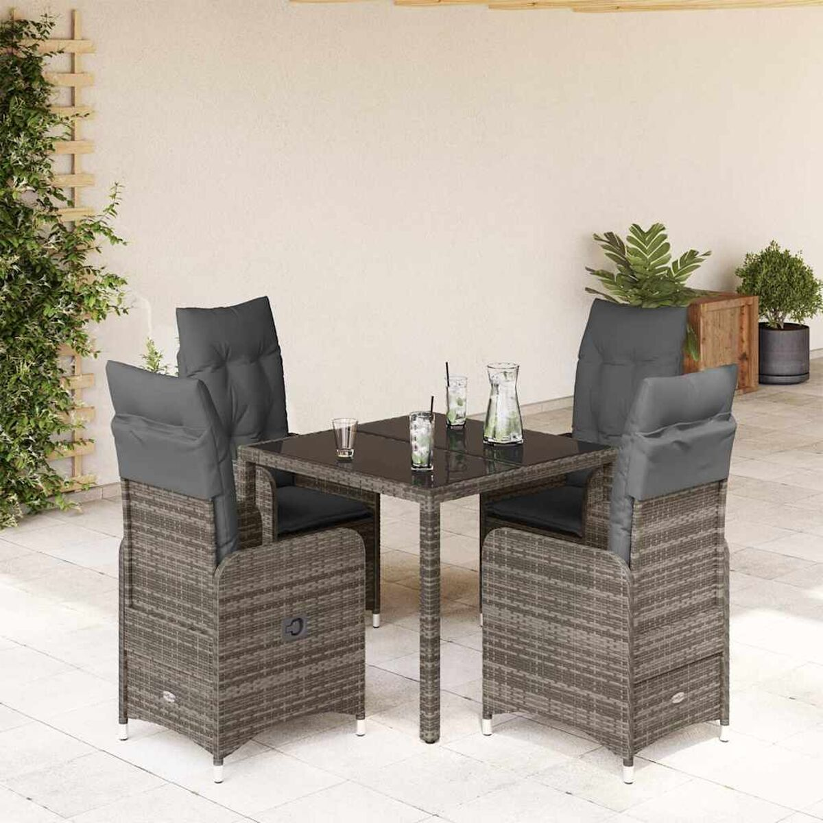 Set da pranzo in rattan da esterno con tavolo, sedie, cuscini e bicchieri sul tavolo.