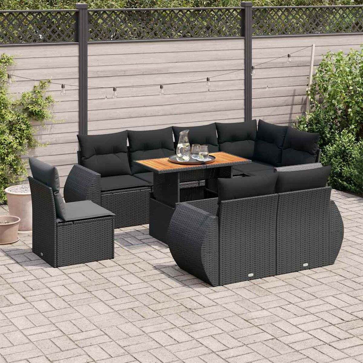 Set di mobili da esterno con divano nero e tavolo. Sfondo del patio in mattoni.