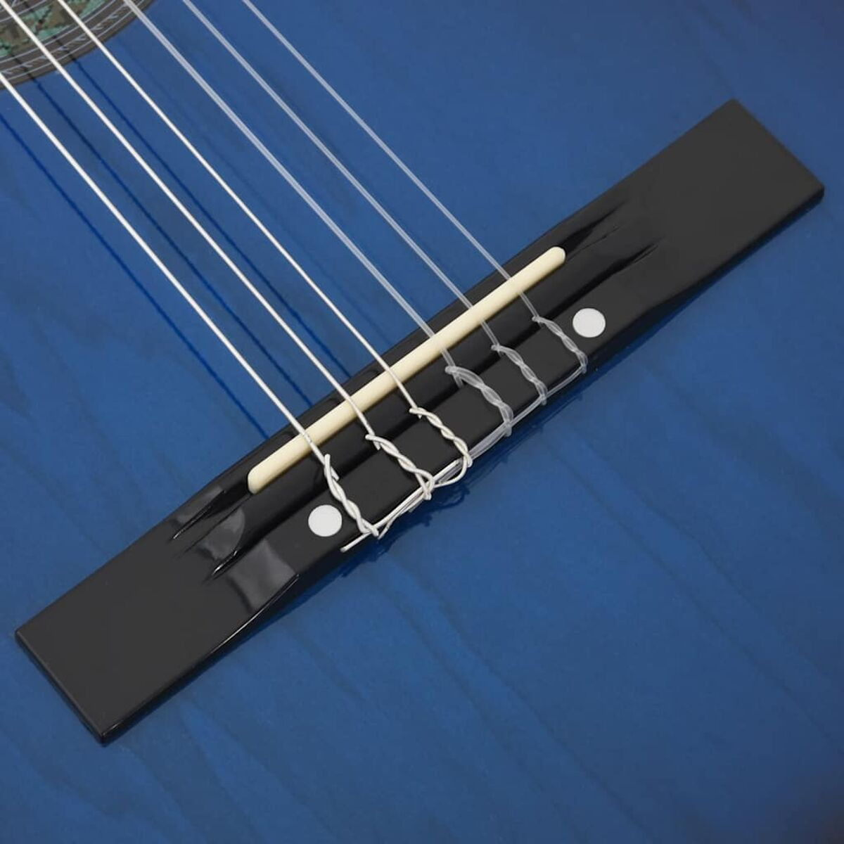 Nahaufnahme eines blauen Gitarrenstegs mit weißen Saiten und einem hellfarbigen Stegstift.