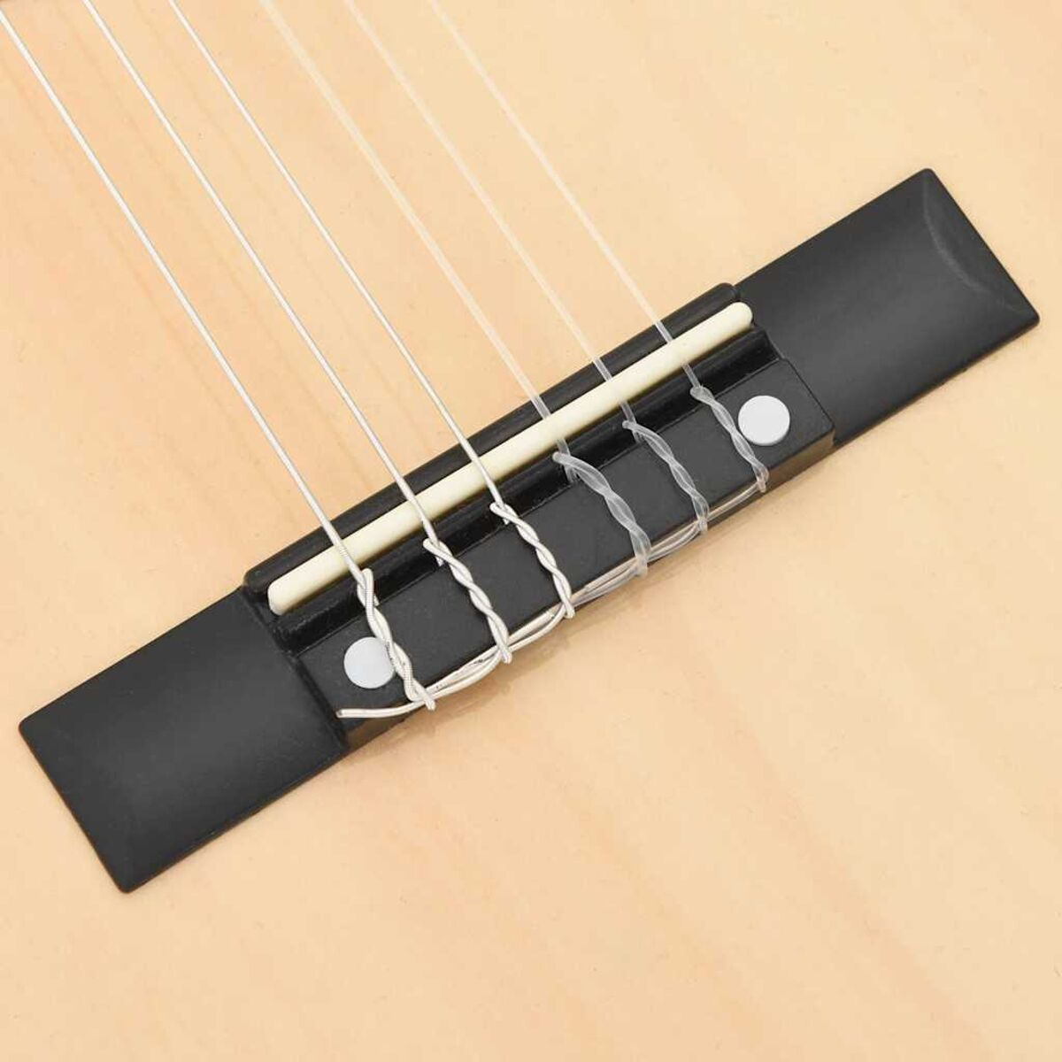 Nahaufnahme einer Gitarrenbrücke mit Saiten. Schwarze Brücke, weiße Saiten, heller Holzkorpus.