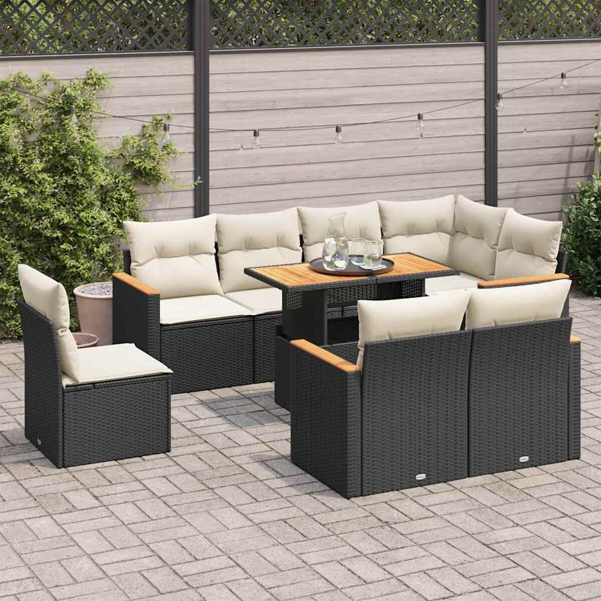 Set di mobili da esterno in rattan nero. Include divano, due sedie e tavolo. Patio in mattoni.