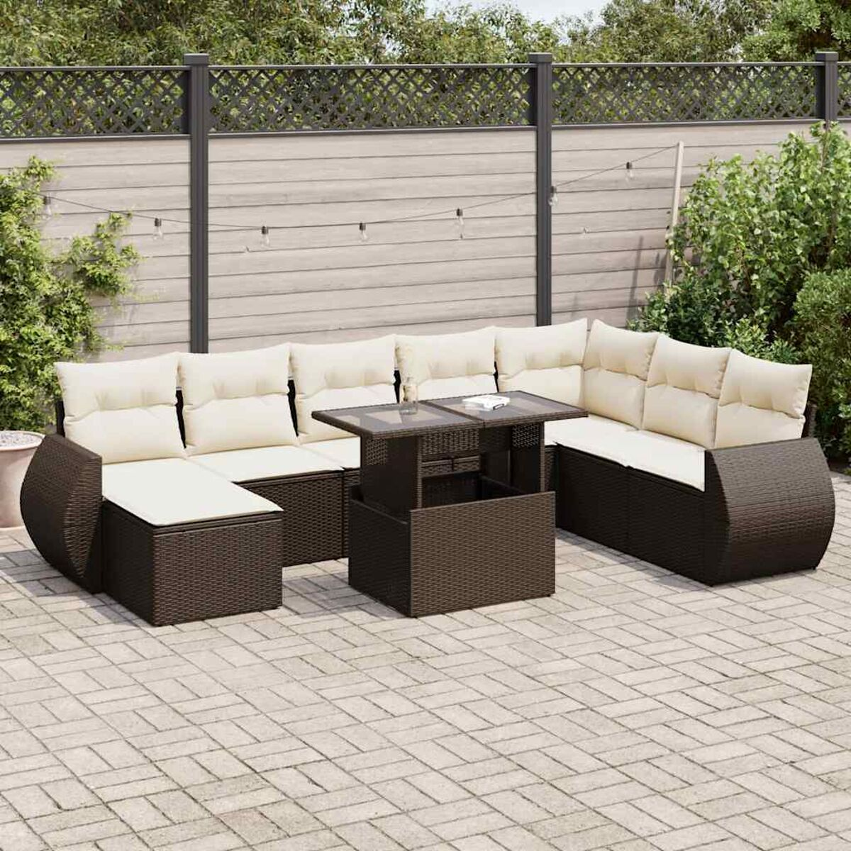 Ein Terrassenmöbel-Set mit Sofa, Eckteil und Tisch. Enthält weiße Kissen und befindet sich draußen.