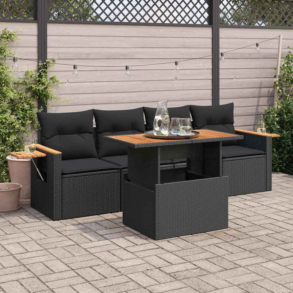 Set di mobili da esterno in vimini nero con tavolo. Cuscini neri, dettagli in legno.
