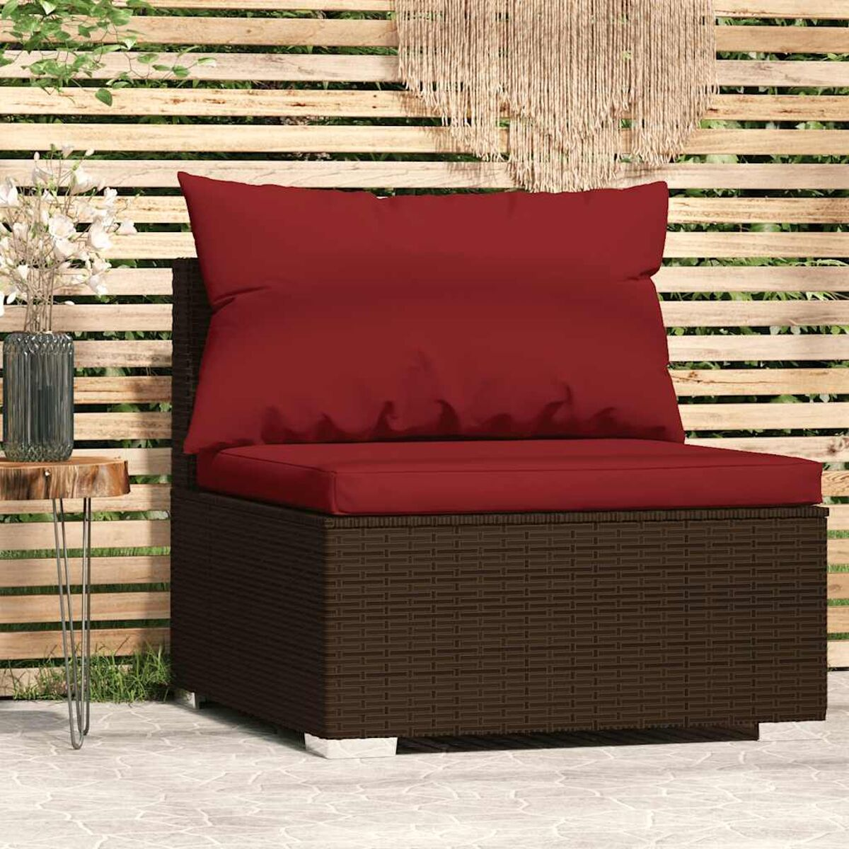 Brauner Rattan-Stuhl im Freien mit rotem Kissen und Kissen auf einer Terrasse.