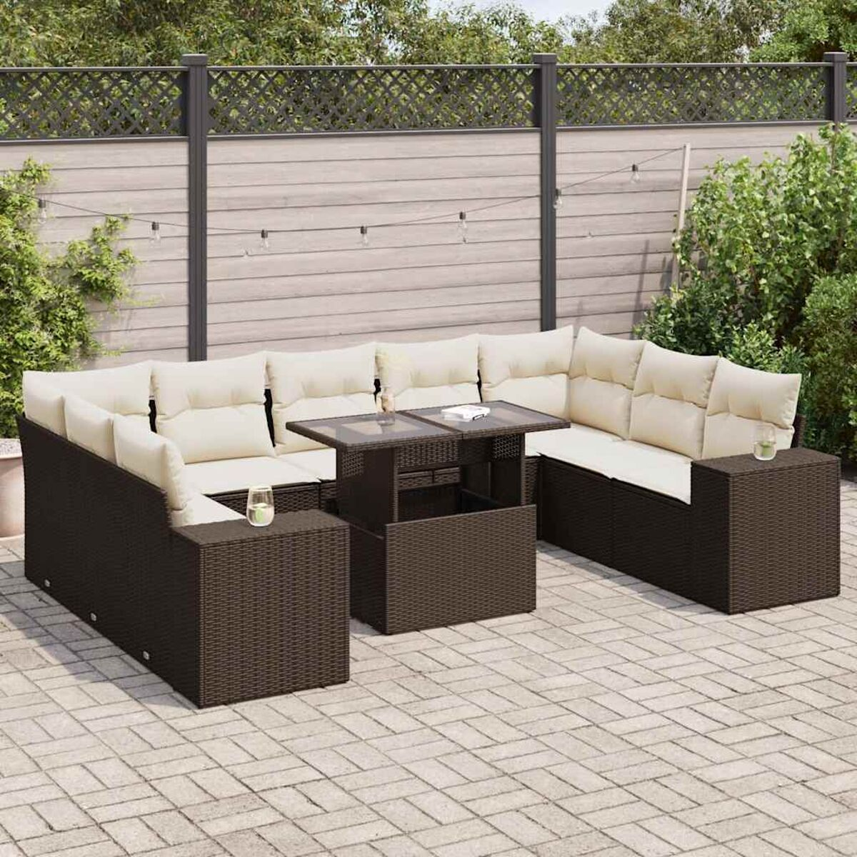 Outdoor-Sitzbereich mit dunkelbraunen gewebten Möbeln, einem Glastisch und beigen Kissen auf einer Terrasse.