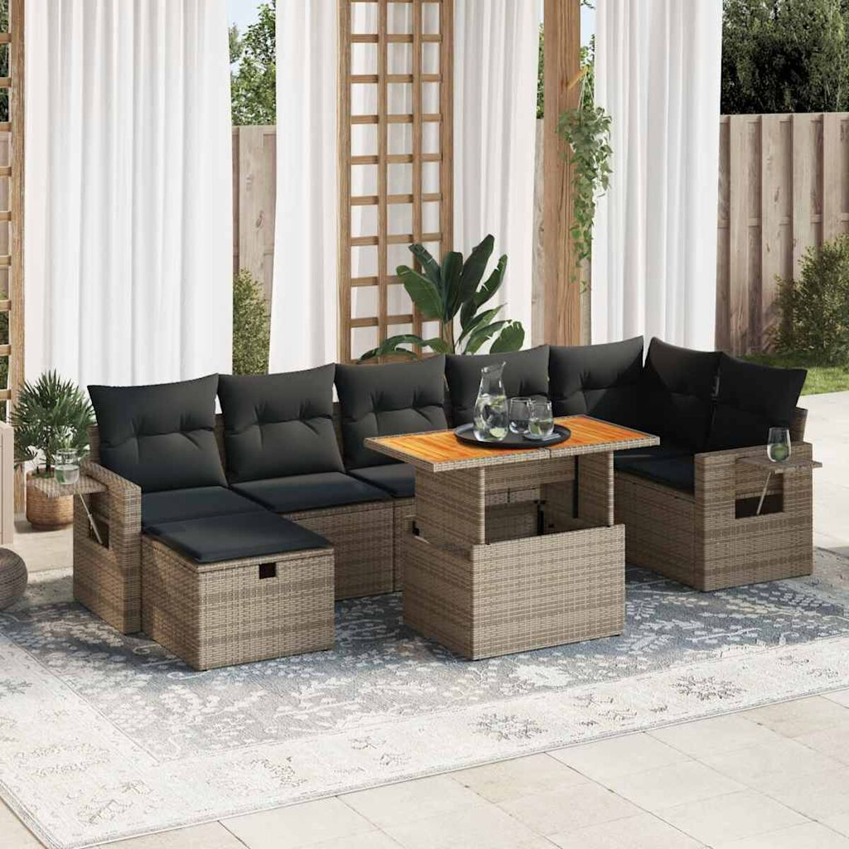 Beiges Outdoor-Sitzmöbelset aus Korbgeflecht mit Tisch und dunklen Kissen. Die Kulisse ist eine Terrasse.