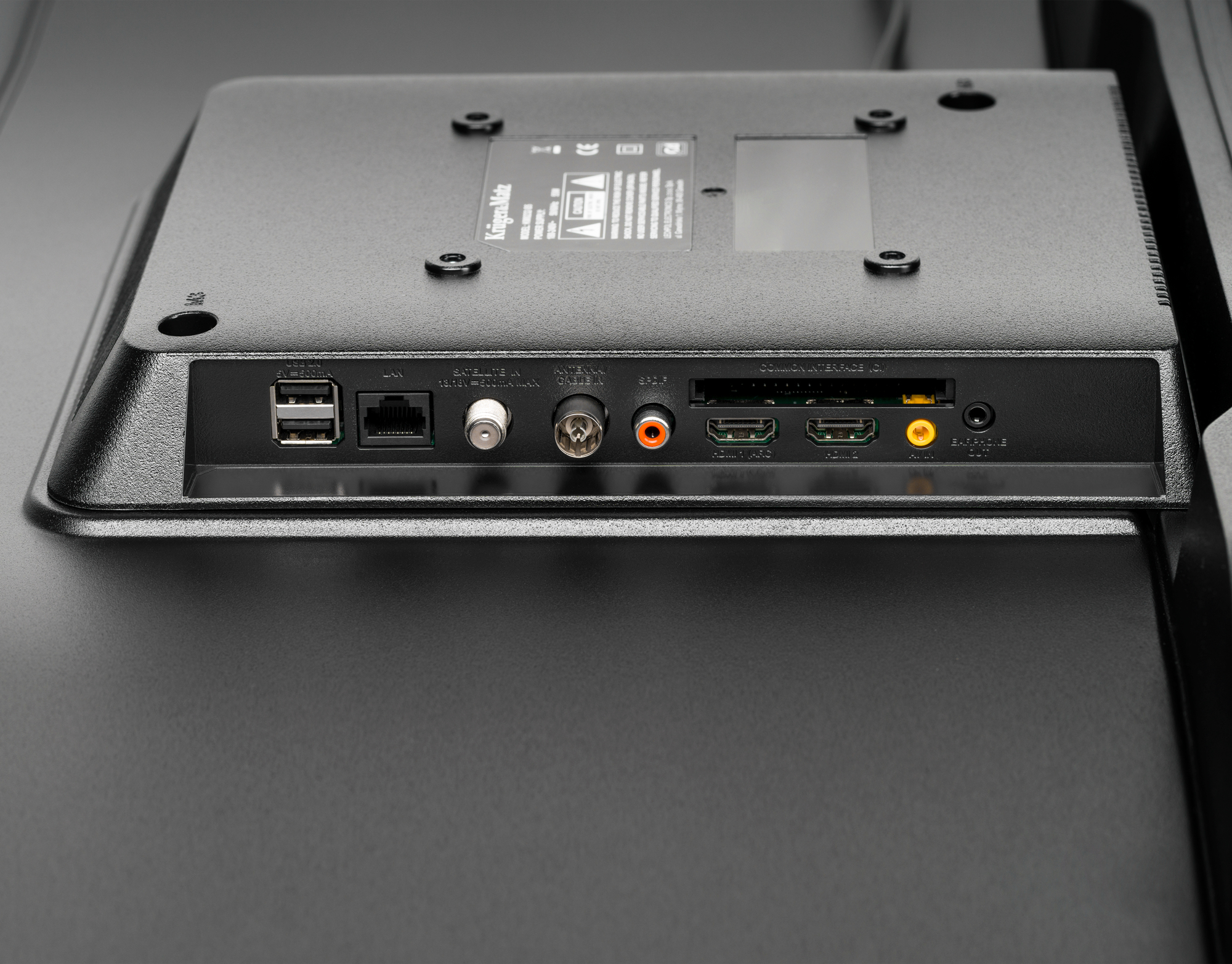 Czarny panel tylny TV z portami: USB, LAN, anteną, audio, HDMI i innymi.