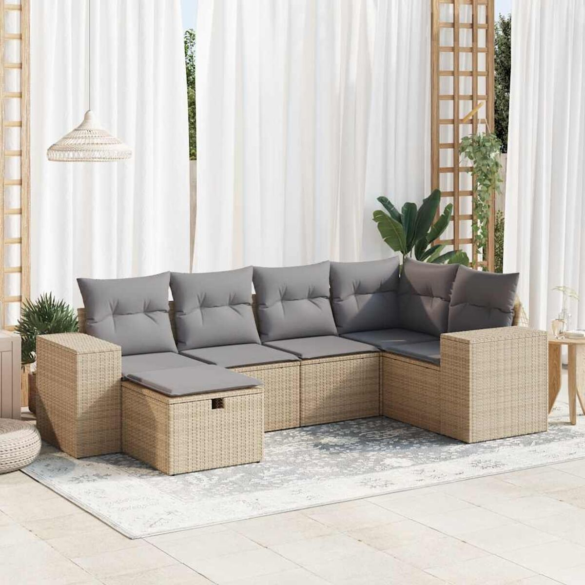 Un set da patio in vimini beige con cuscini grigi e un tappeto colorato chiaro.