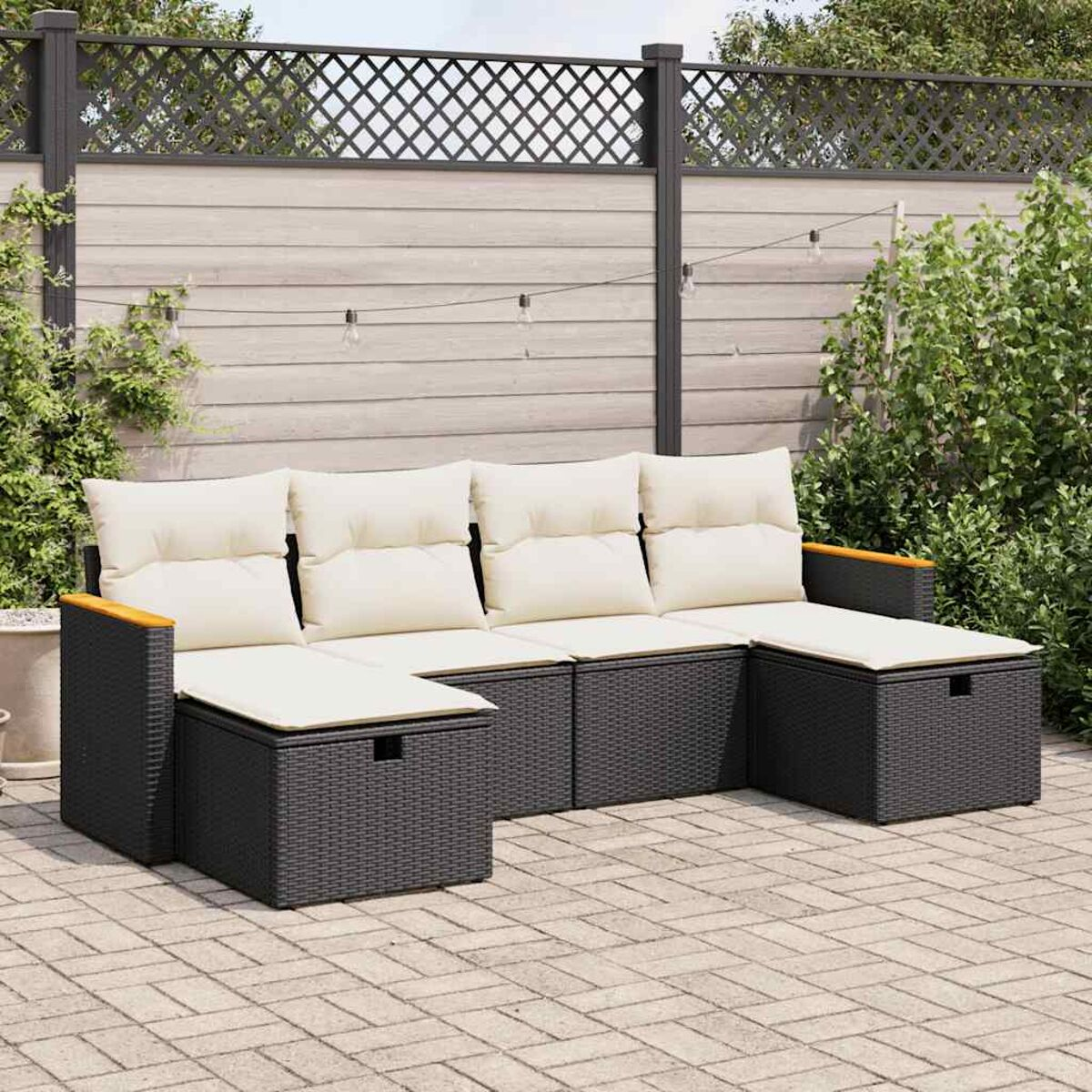 Outdoor-Ecksofa auf Backstein-Terrasse, dunkelgraues Korbgeflecht mit cremefarbenen Kissen.