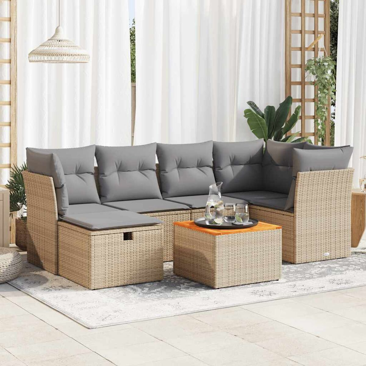 Geflochtenes Outdoor-Sofaset mit Kissen und Couchtisch. Die Szene ist auf einer Terrasse mit weißen Vorhängen.