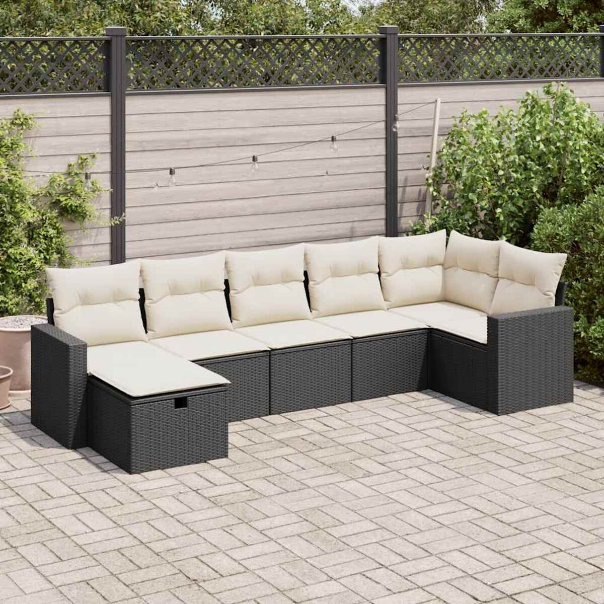 Garten-Ecksofa mit beigen Kissen auf Backsteinpflasterung, mit Holzzaun.