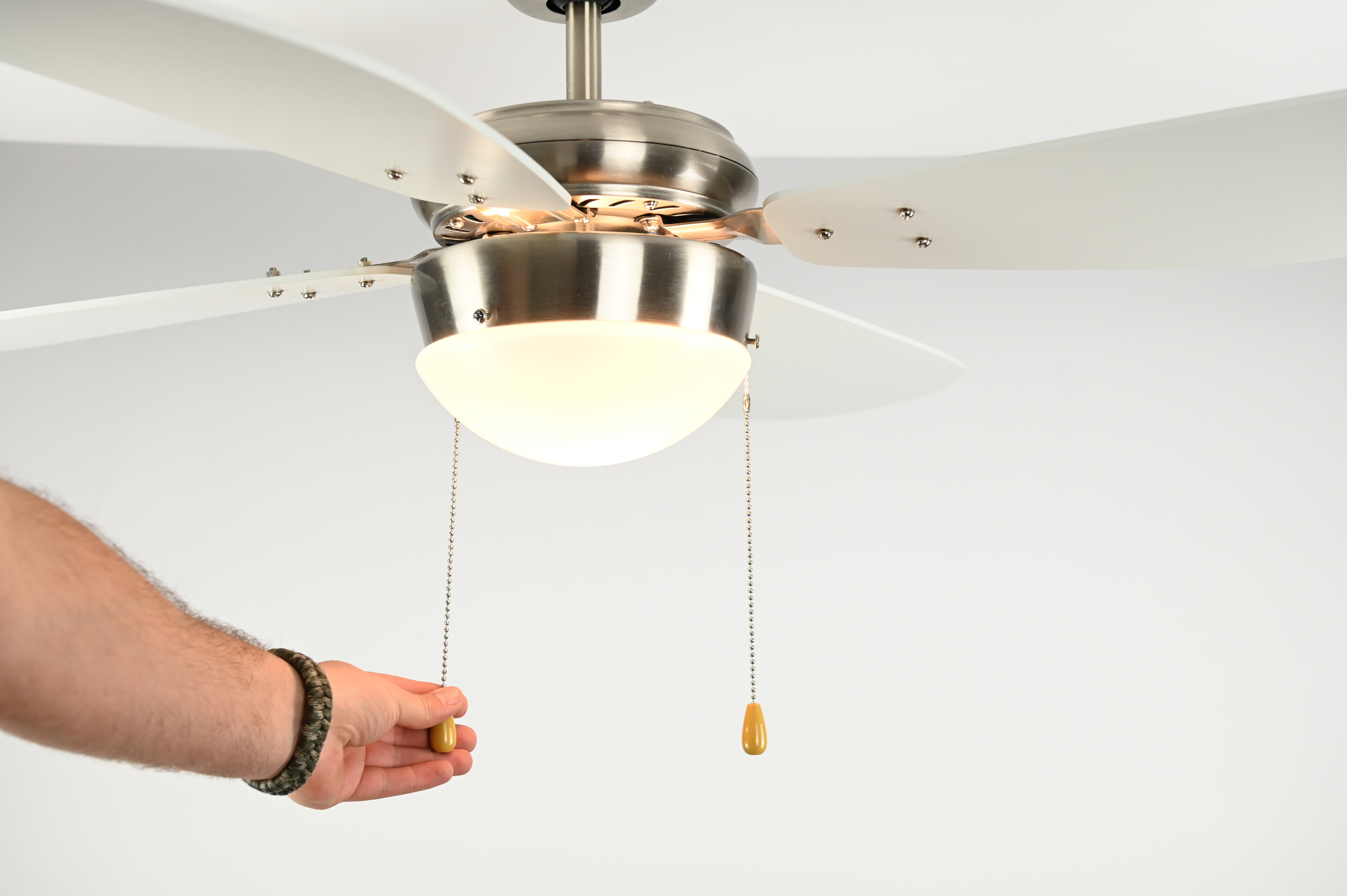 Nahaufnahme eines Deckenventilators, der die Halterung und die Flügel des Ventilators vor einer weißen Decke zeigt.