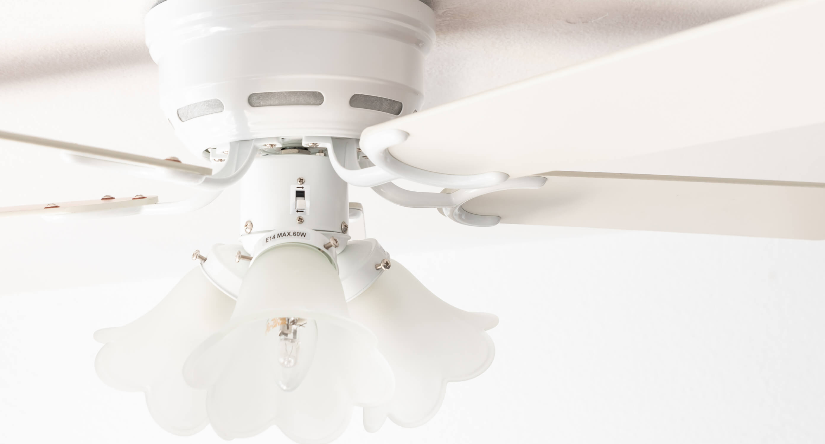 Ventilatore da soffitto bianco con tre luci. Le luci hanno un design a petalo.