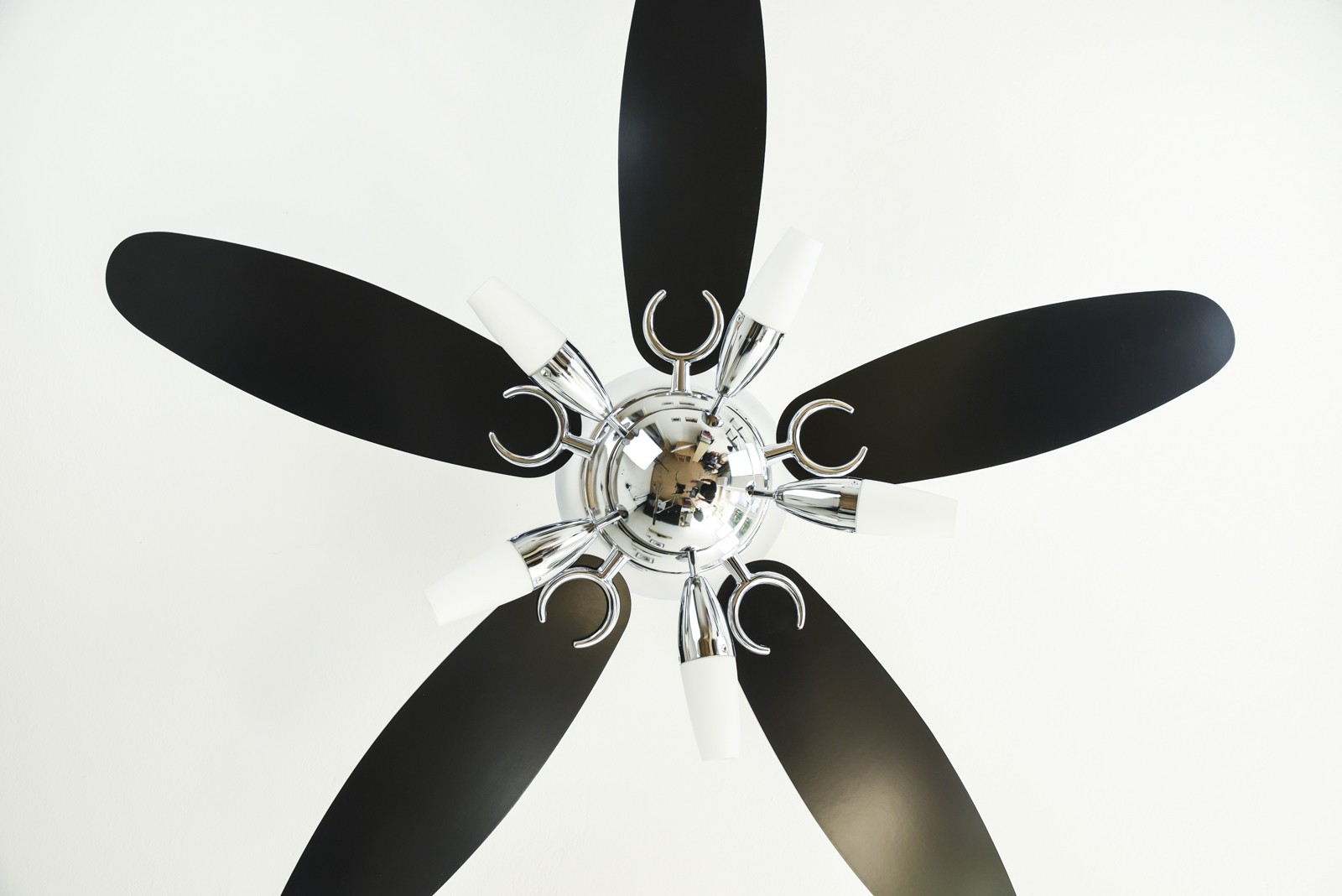 Deckenventilator mit schwarzen Flügeln und Chromakzenten.