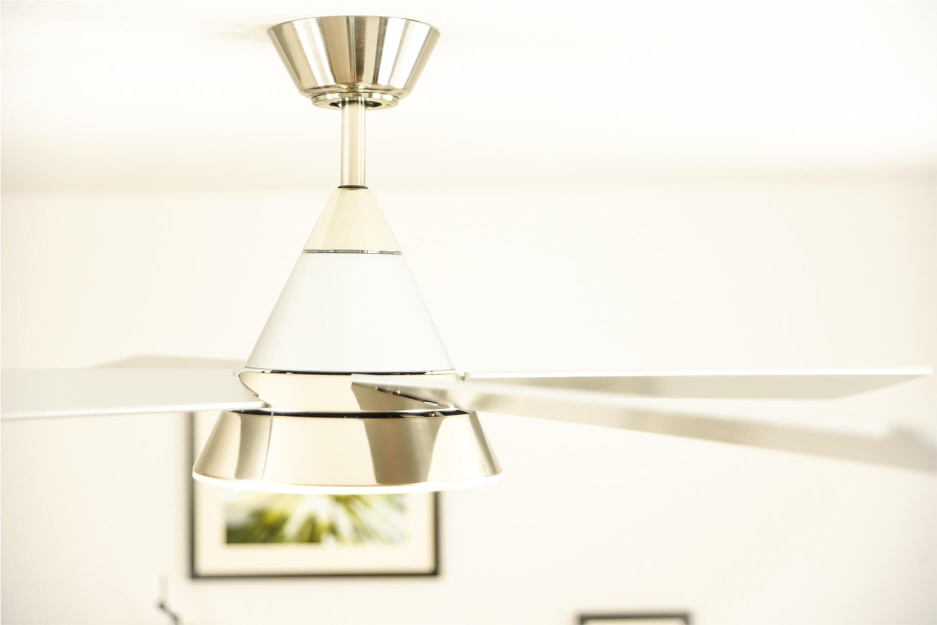 Ventilatore da soffitto bianco e argento con pale bianche. Montato su un soffitto bianco.