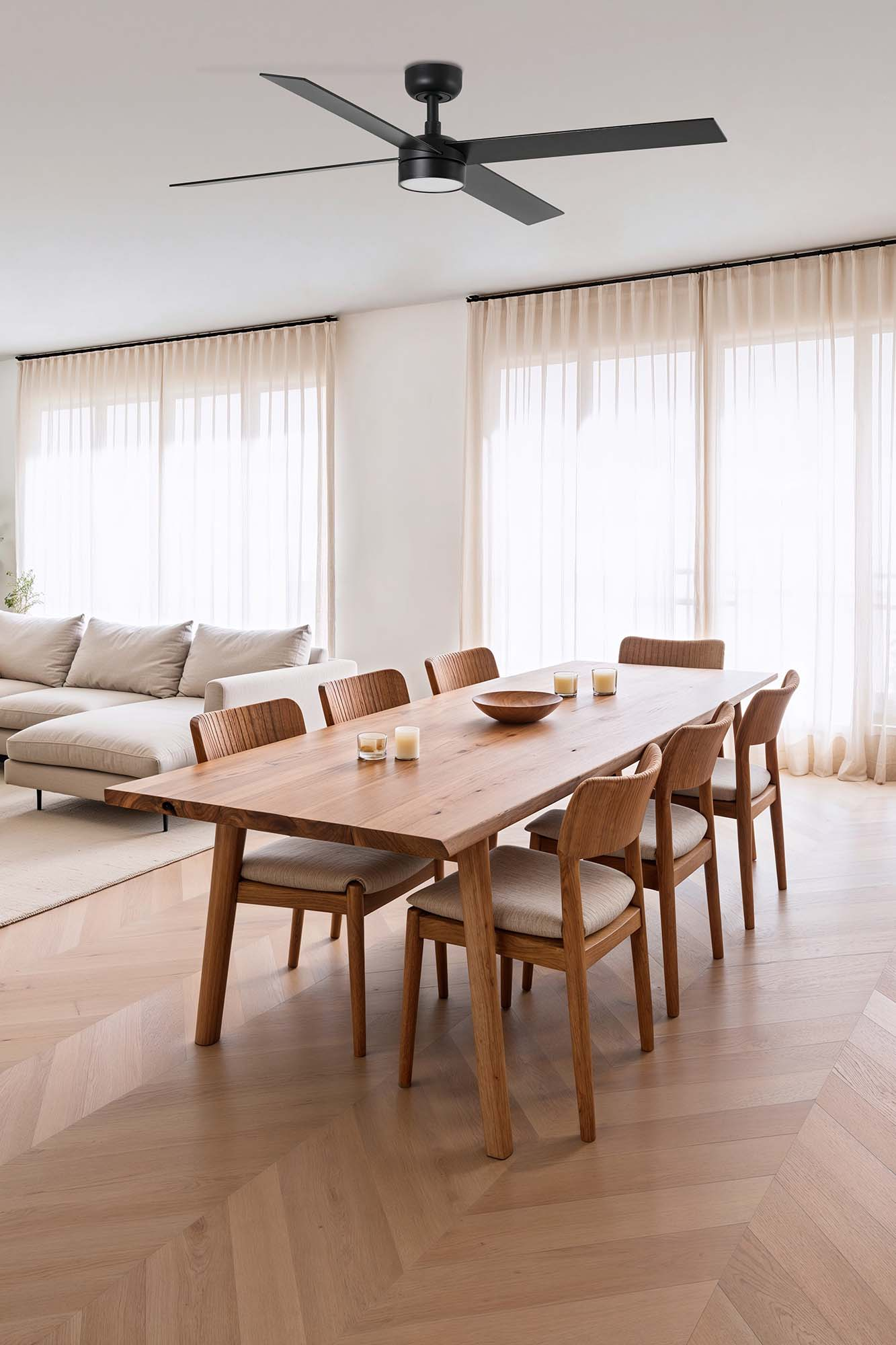 Ein modernes Esszimmer mit einem Holztisch, Stühlen und Deckenventilator. Große Fenster.