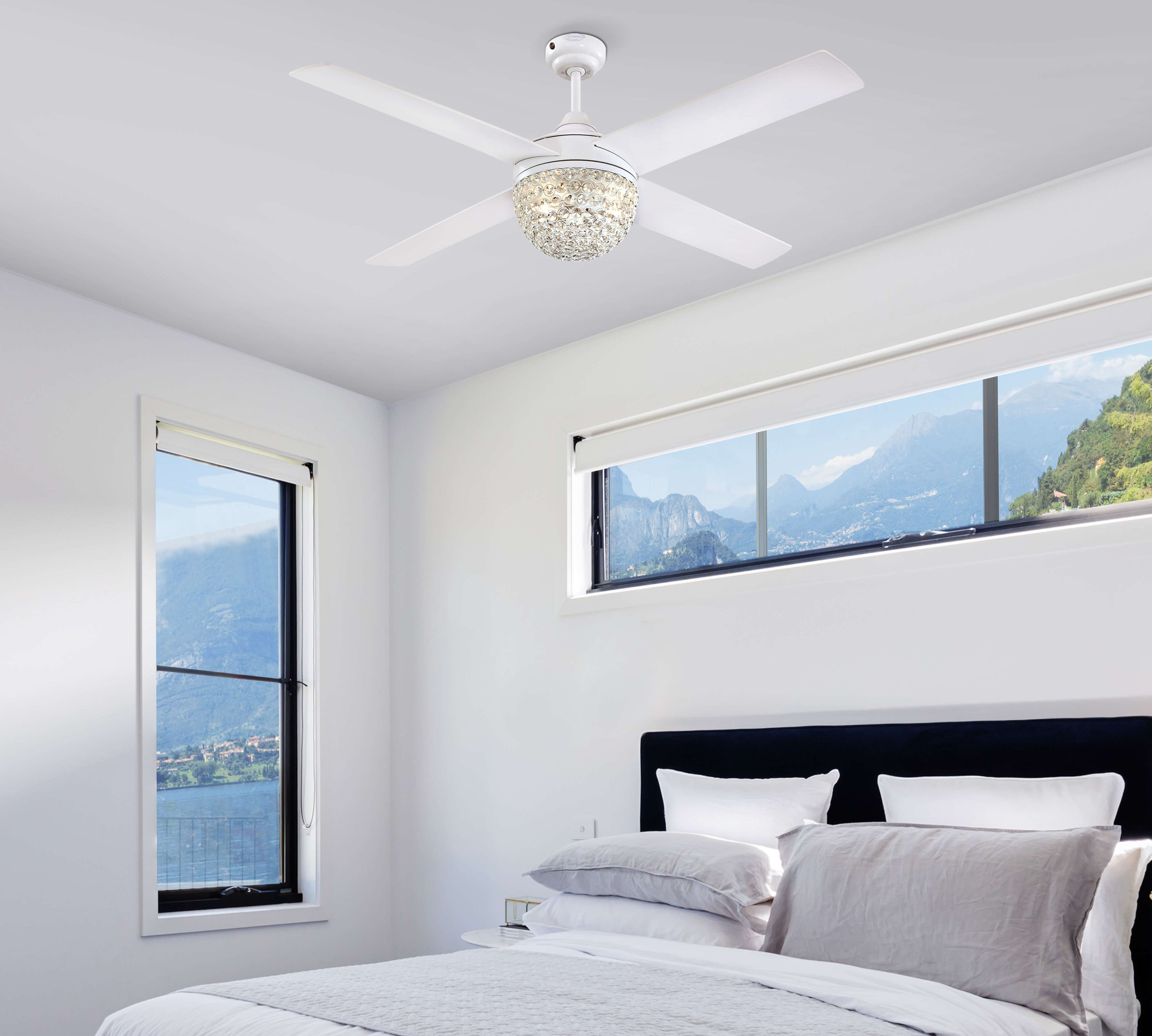 Schlafzimmer mit weißem Deckenventilator, Bett und Fenstern mit Landschaftsblick.