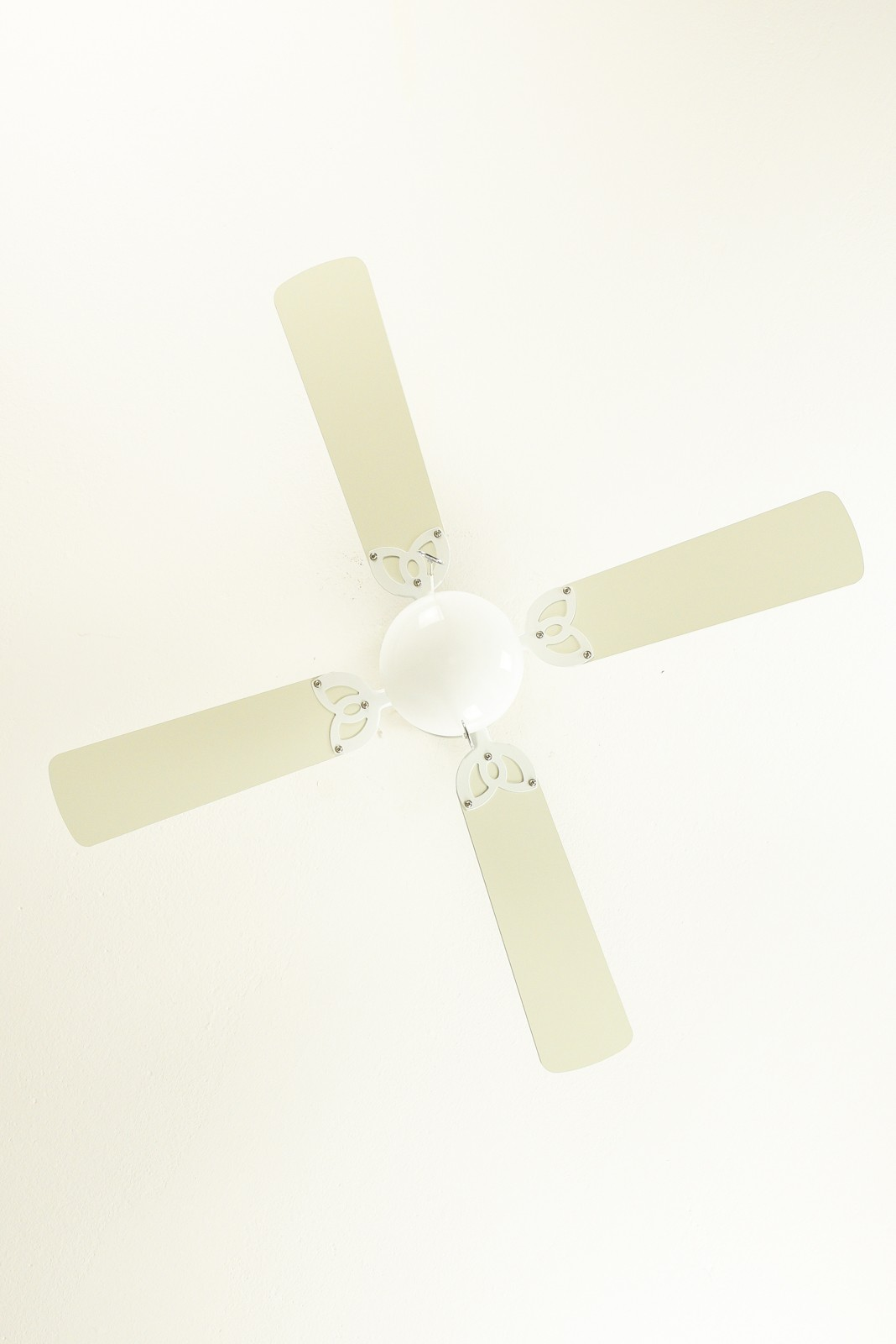 Deckenventilator mit vier cremefarbenen Flügeln, weißem Zentrum und weißer Decke.