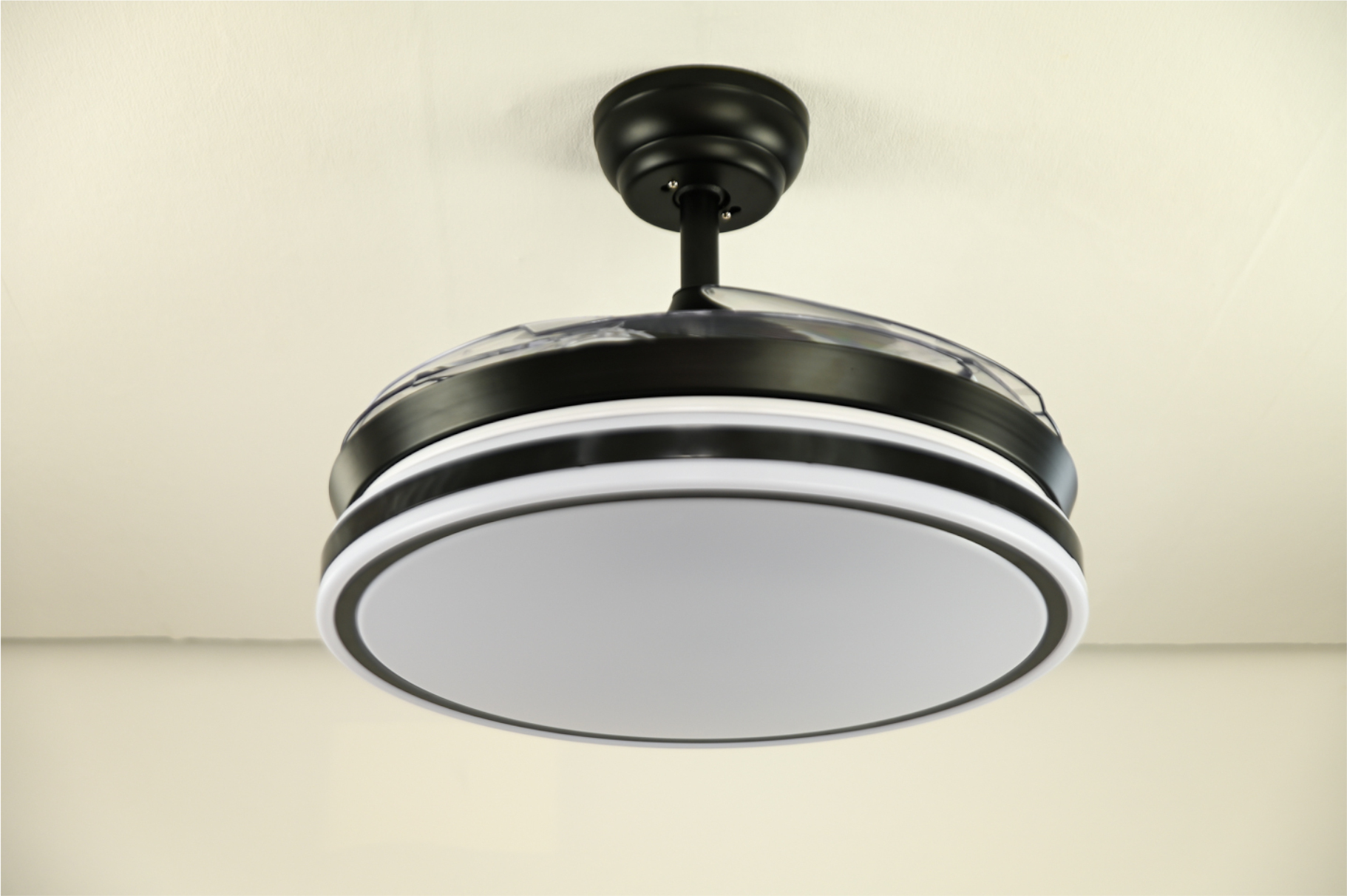 Ein schwarzer Deckenventilator mit weißem Lichtring und weißer Decke im Hintergrund.