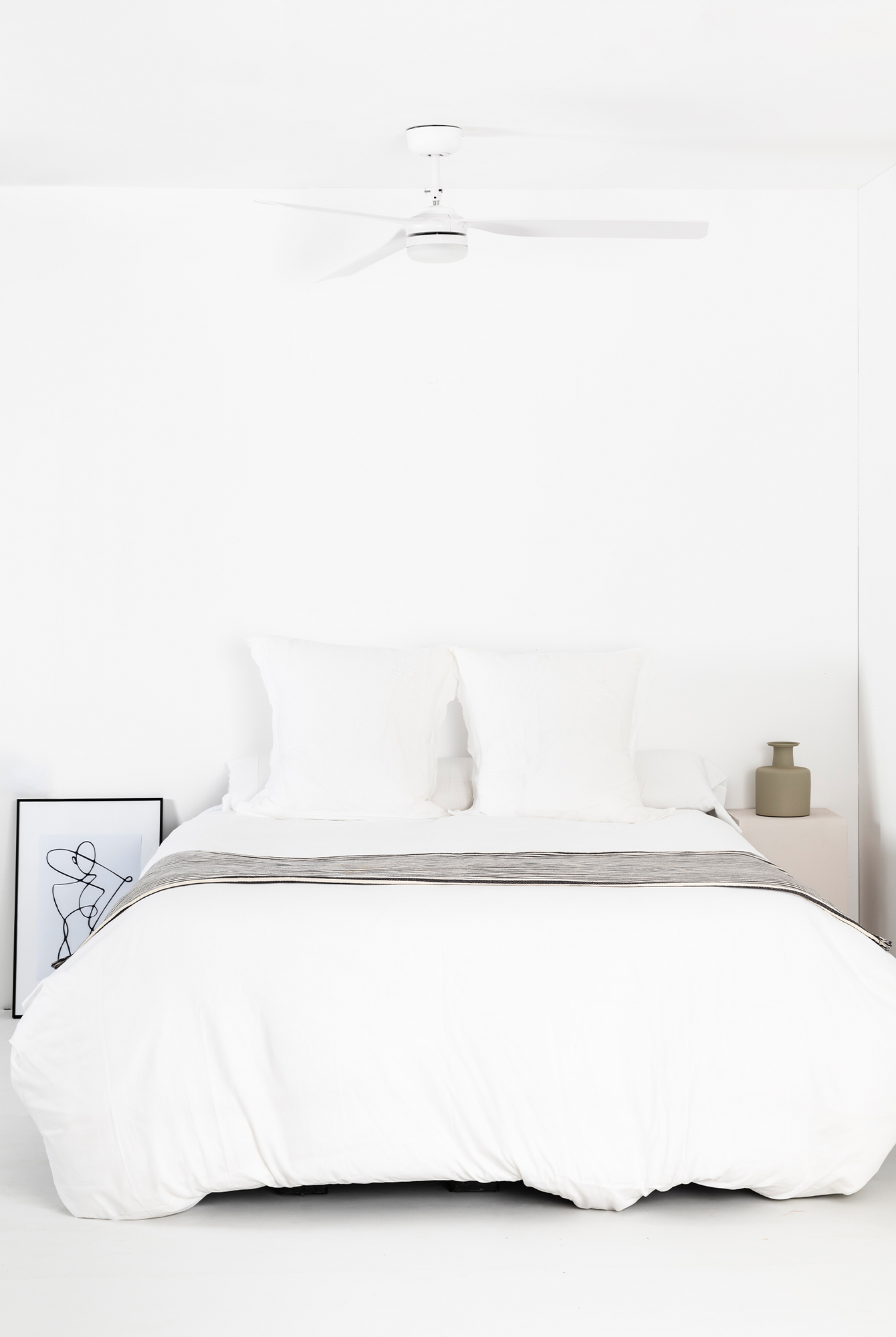 Schlafzimmer-Szene, weiße Wände und Decke, mit weißem Bett und Ventilator.