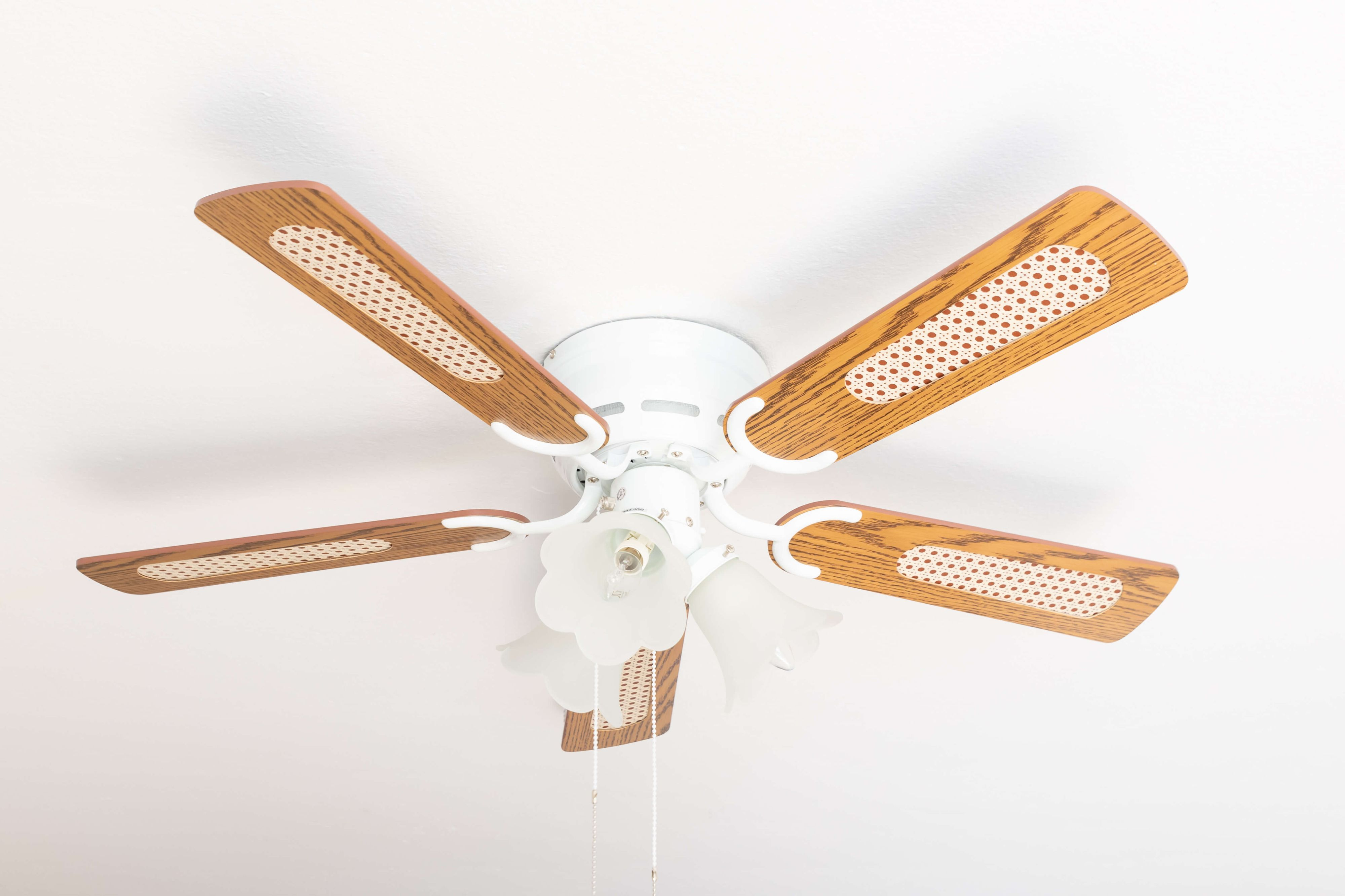 Deckenventilator mit fünf Flügeln, weißem Sockel und Leuchten. Die Flügel sind braun.