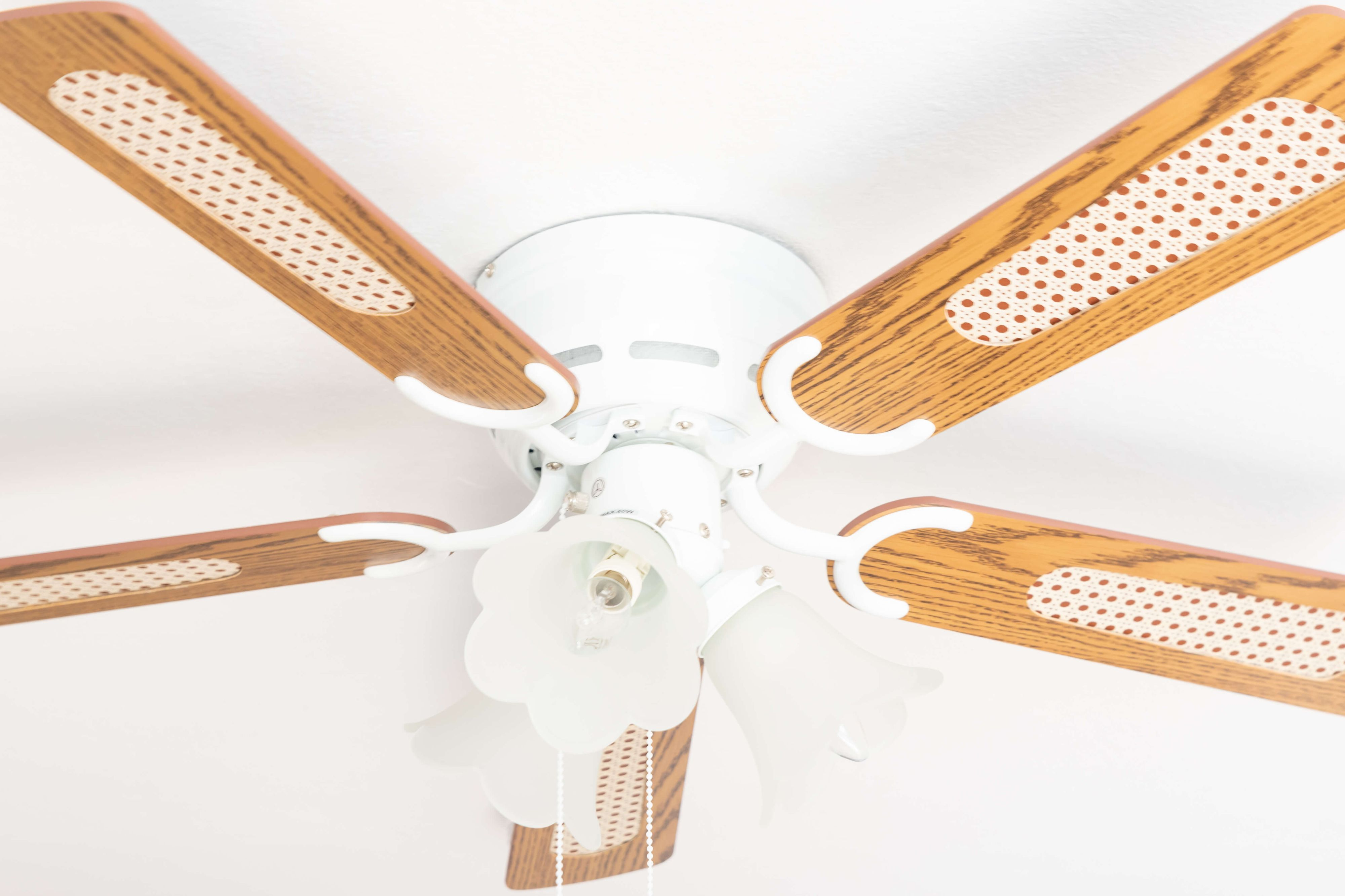 Deckenventilator mit Leuchte. Holzflügel und weißer Sockel.