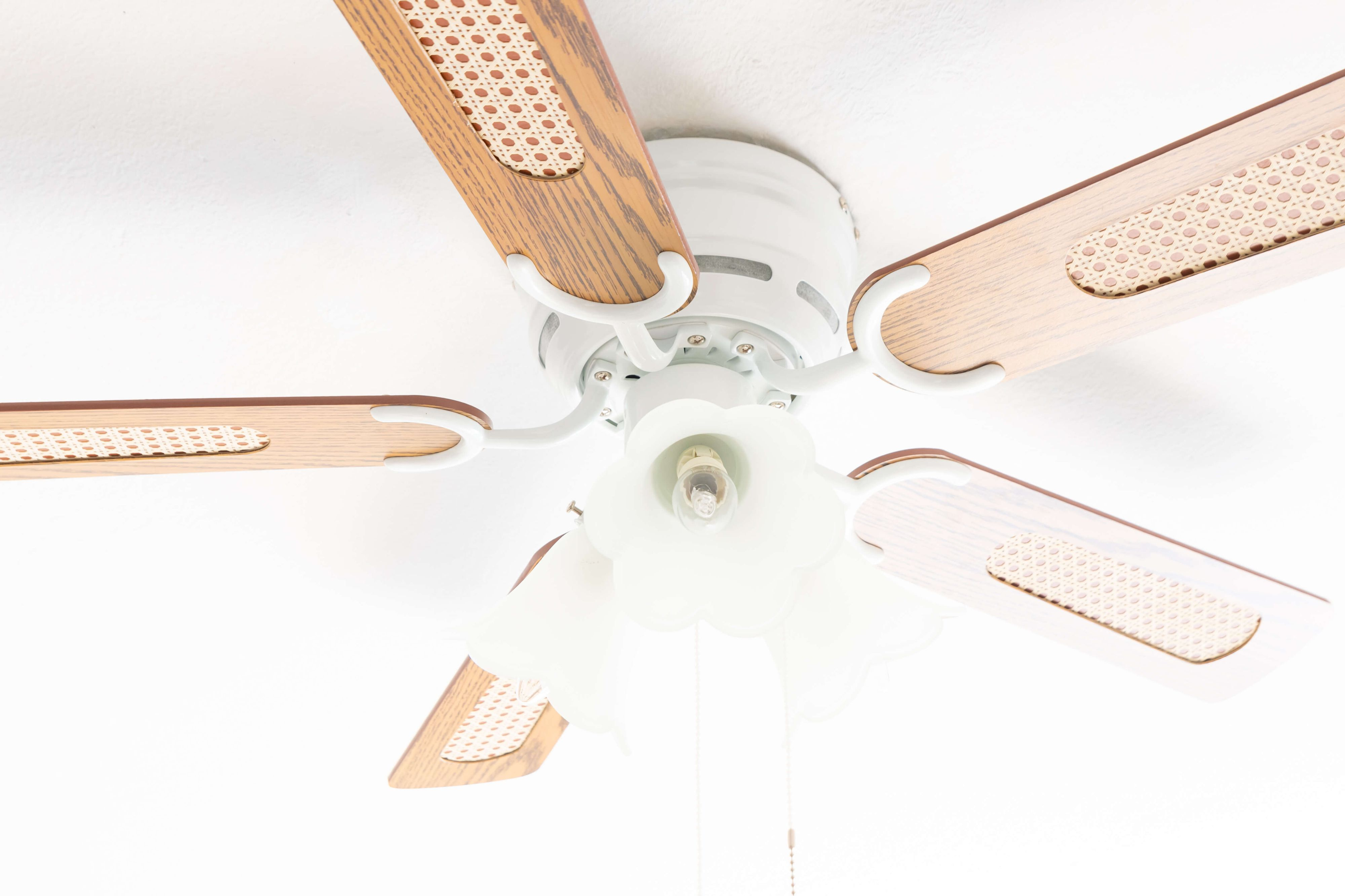 Deckenventilator mit vier Flügeln und dekorativer Leuchte.